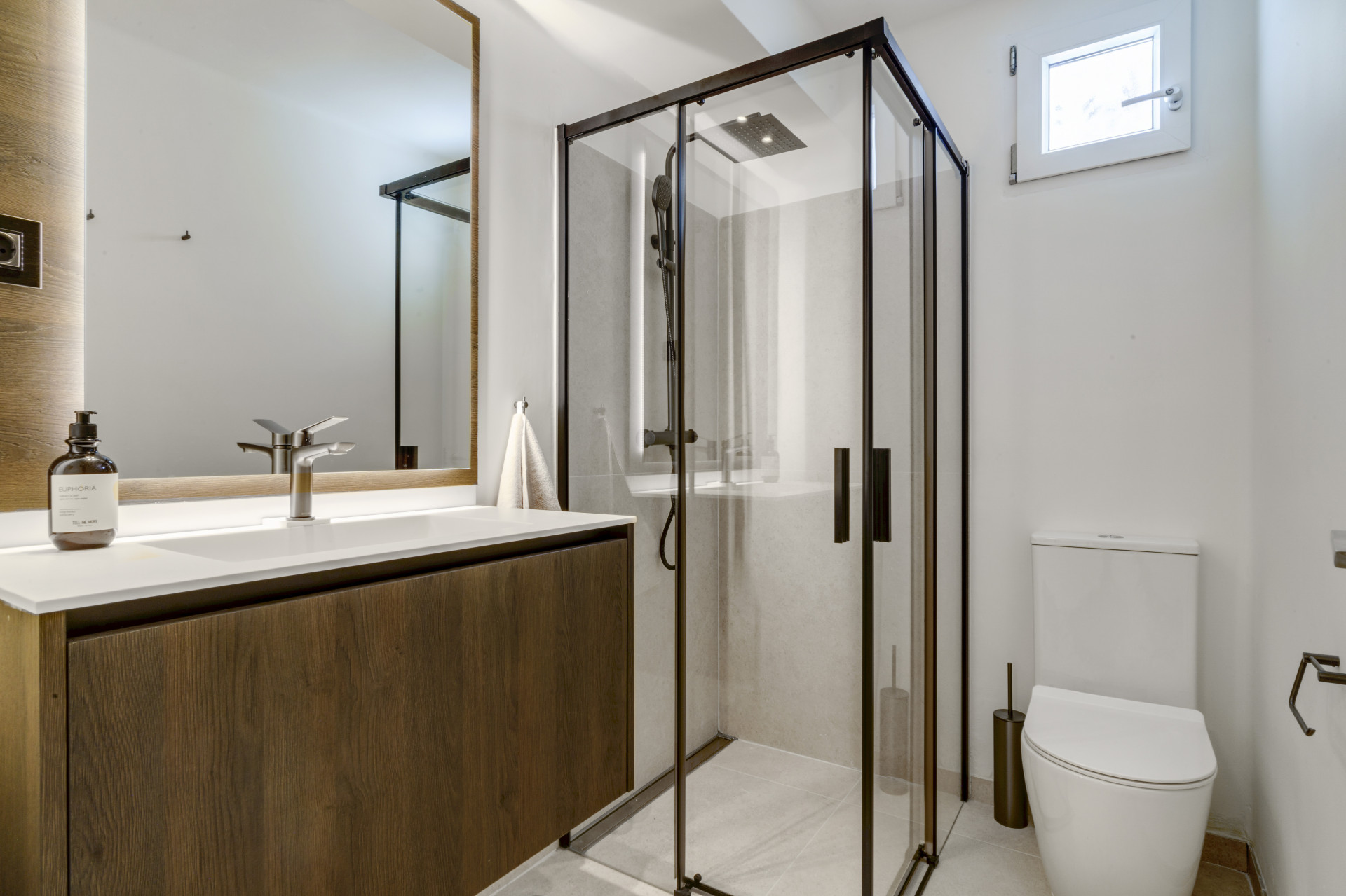 Stylish bathroom showcasing a glass shower, wooden vanity, and modern fixtures.