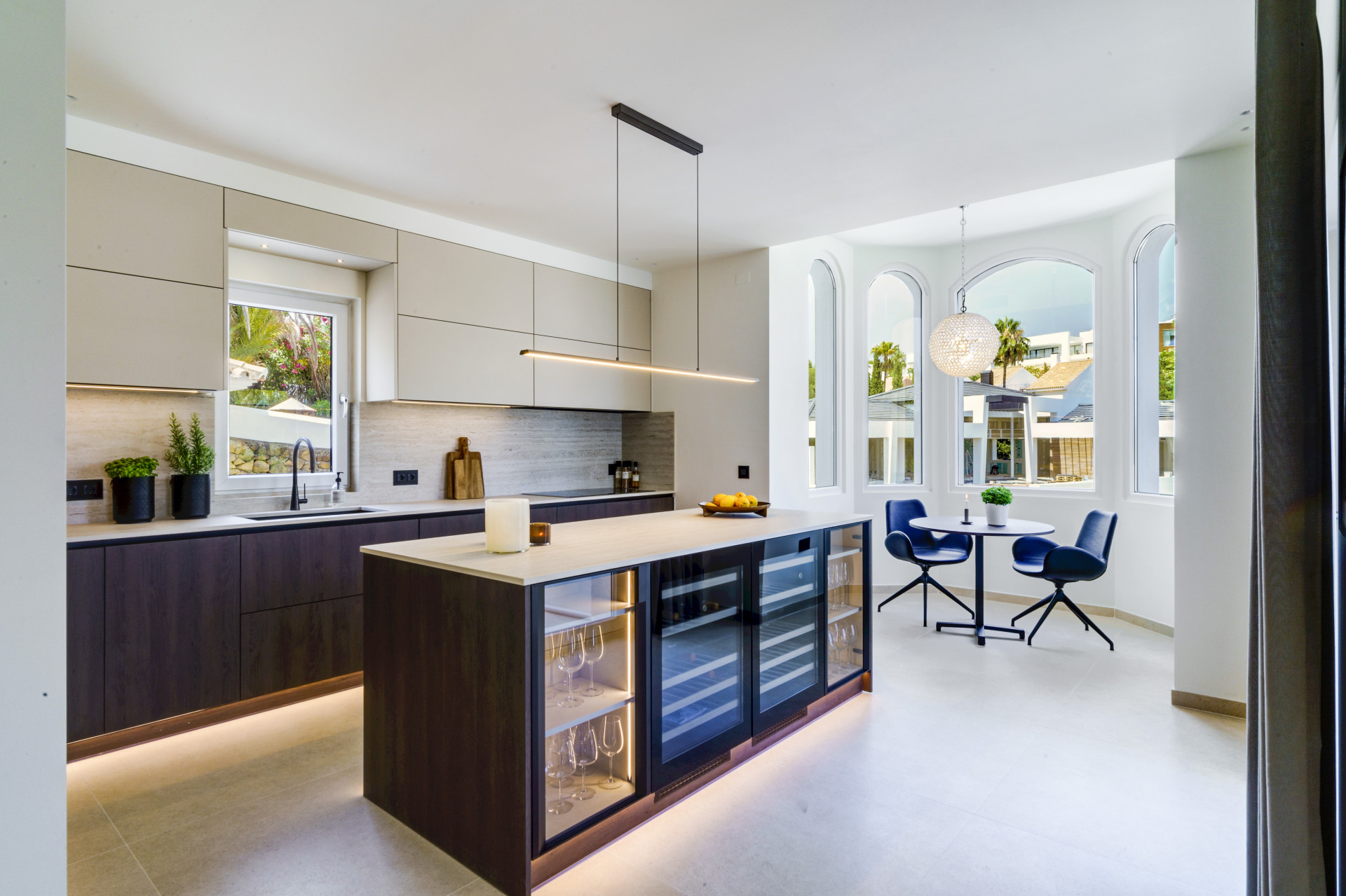 Modern kitchen with a central island, ample cabinets, and a small dining space with large windows.