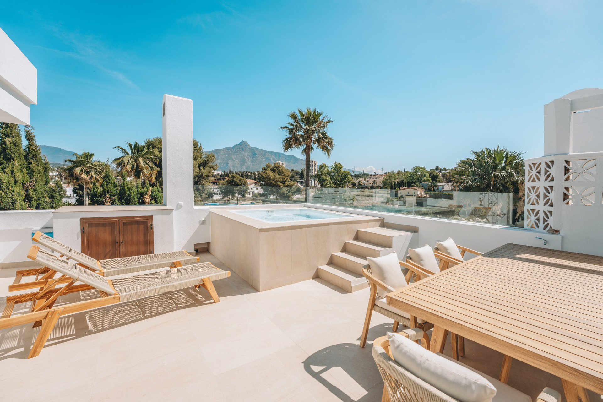 Rooftop terrace with a large outdoor dining table, two sun loungers, and a raised jacuzzi.