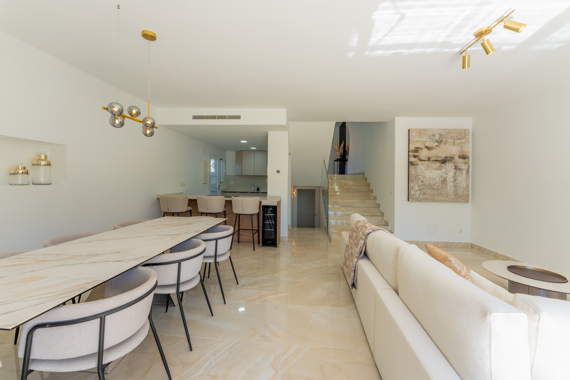 Open concept living and dining area with a visible kitchen, staircase, and contemporary furniture.