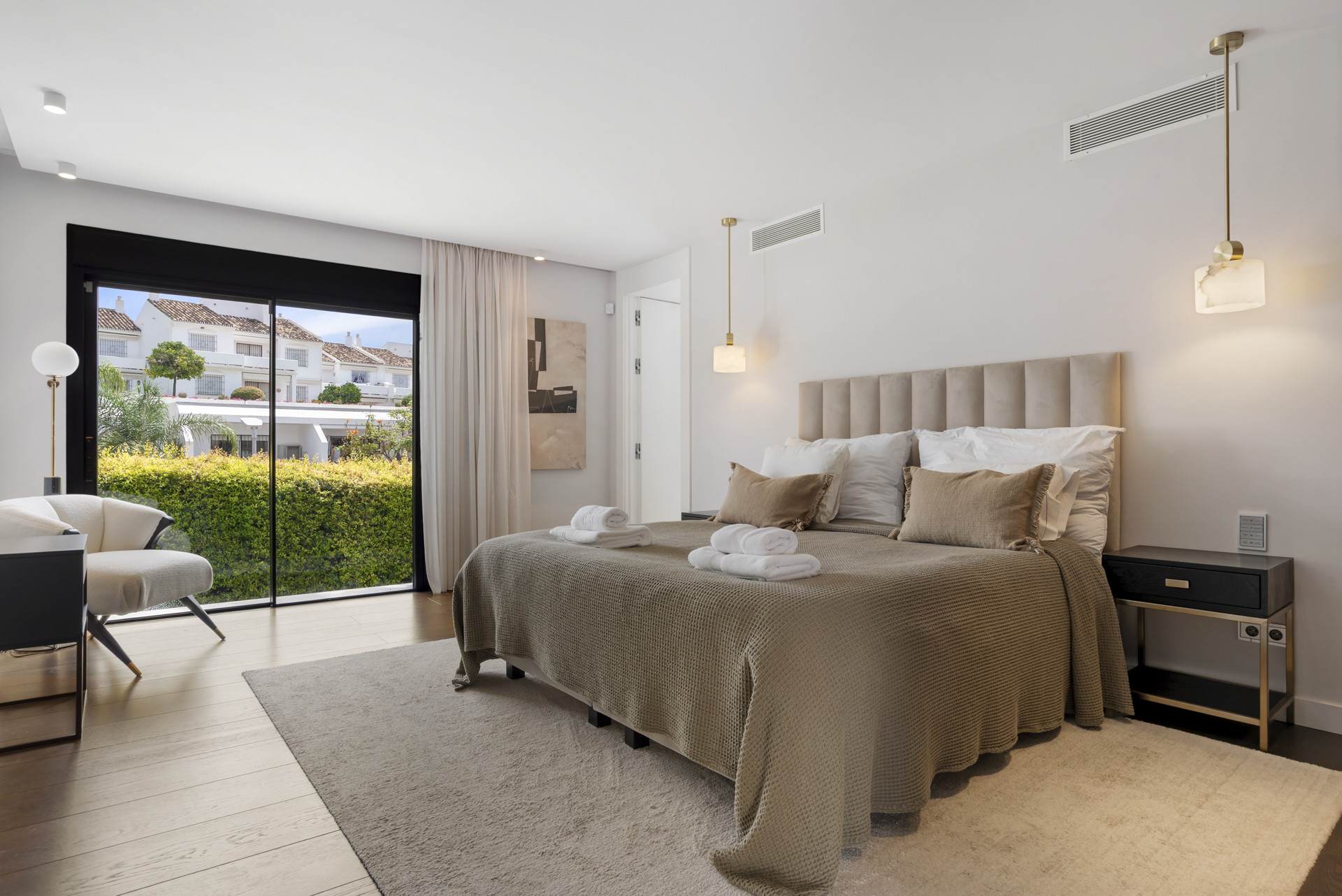 Spacious bedroom with a king bed, modern decor, and large glass doors to a patio.