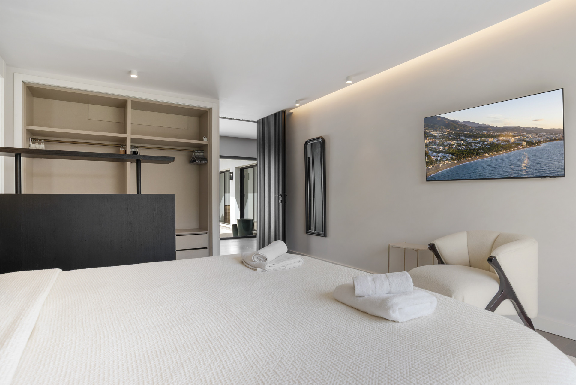 Stylish bedroom with a TV, closet area, and soft decor.