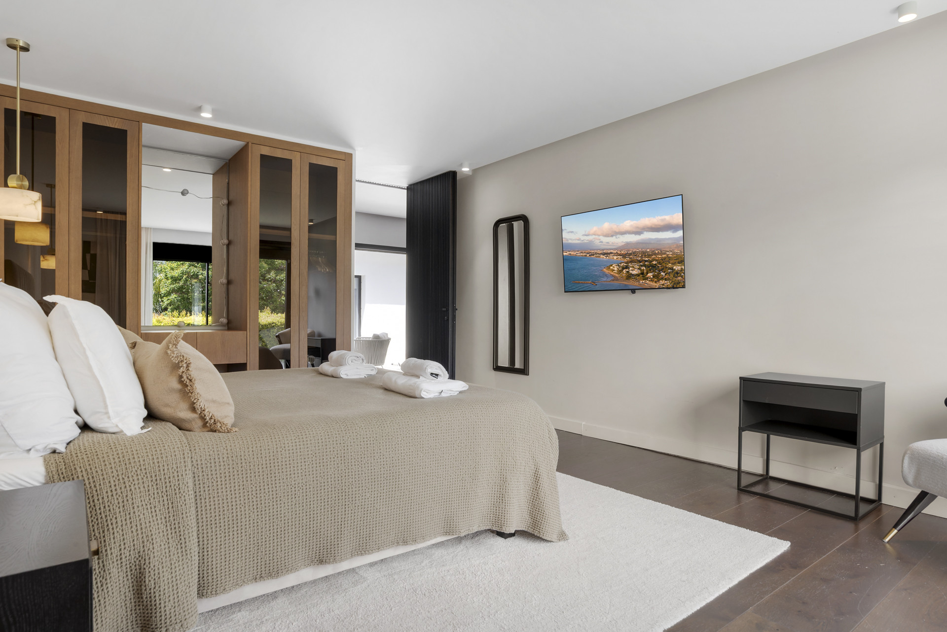 Elegant bedroom featuring a TV, wardrobe, and a view of the garden.
