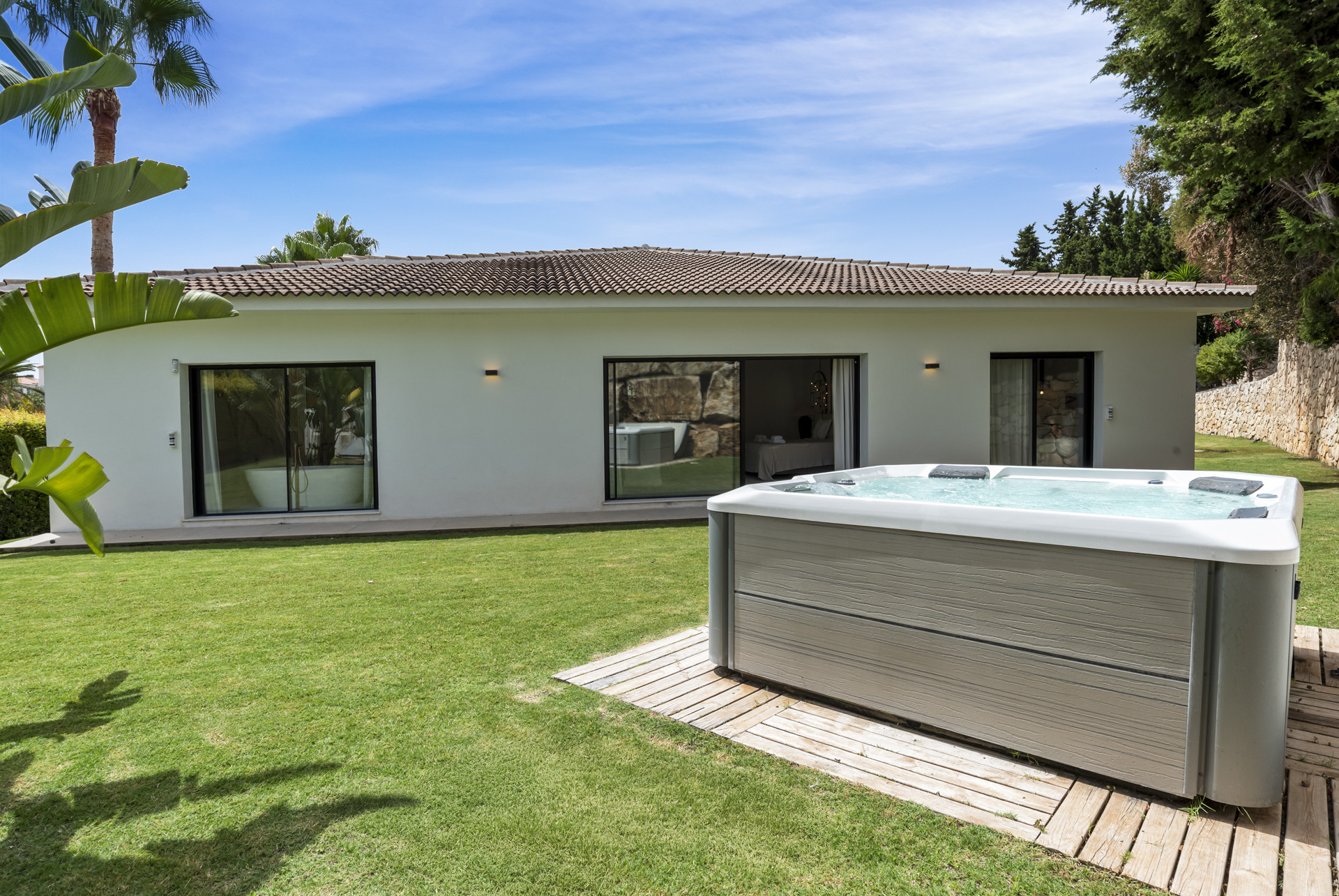 Outdoor view of a garden with a hot tub and sliding doors.