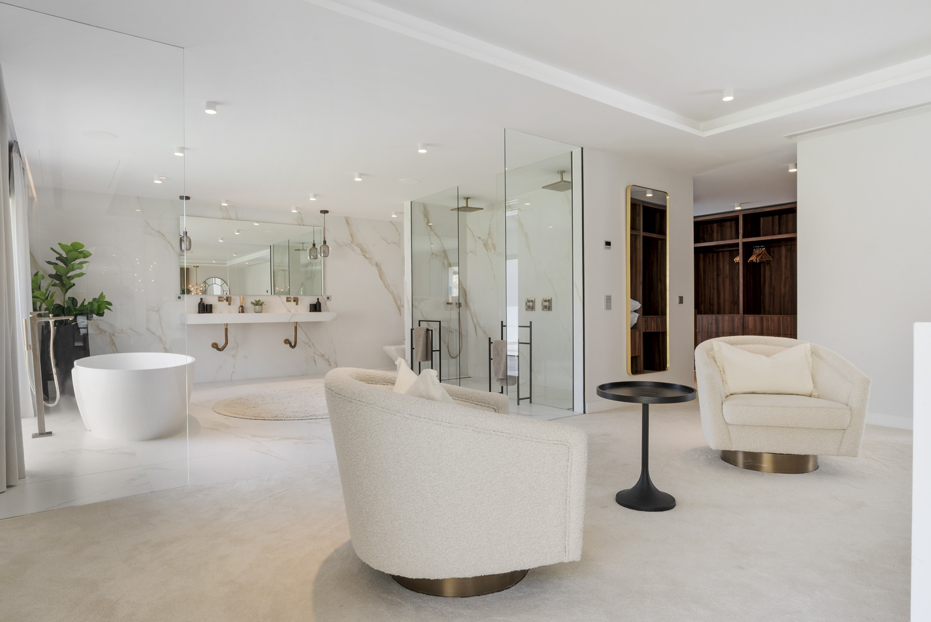 Luxurious bathroom with a freestanding tub, dual sinks, and glass-enclosed shower area with marble accents.