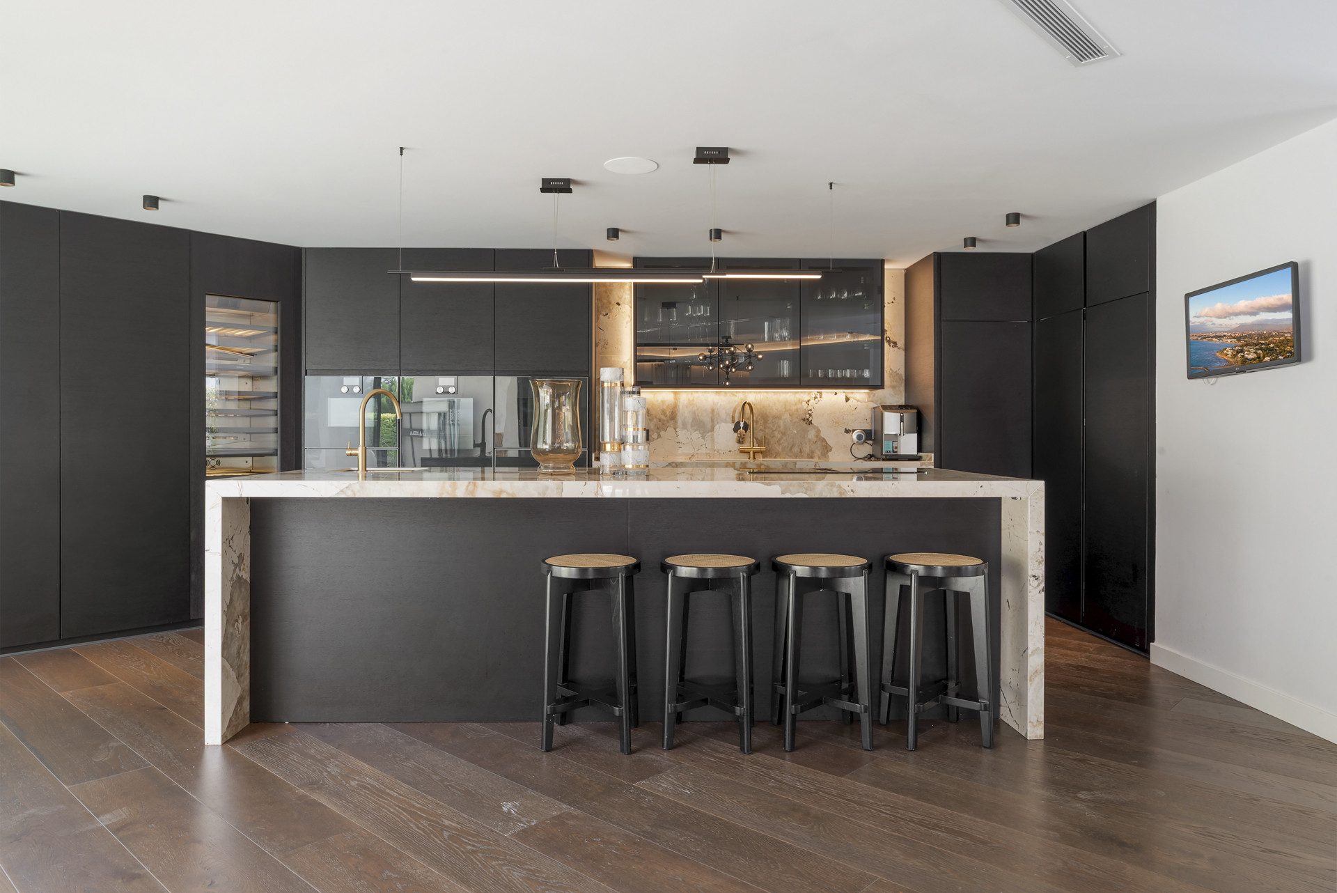 Modern kitchen featuring dark cabinetry, marble island, and wine fridge.