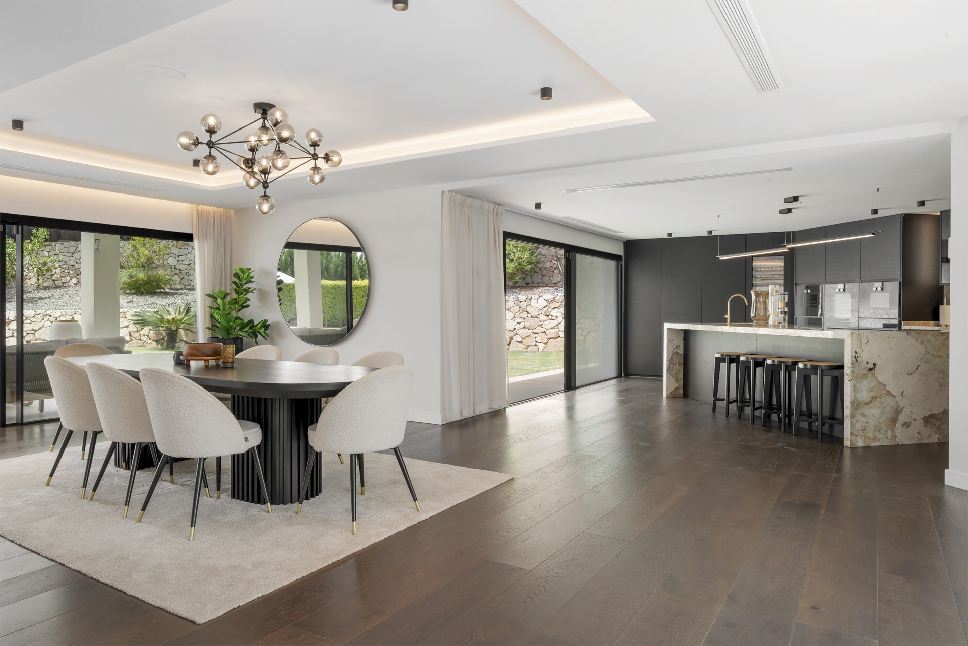 Open plan dining and kitchen with stylish bar seating and large glass doors.