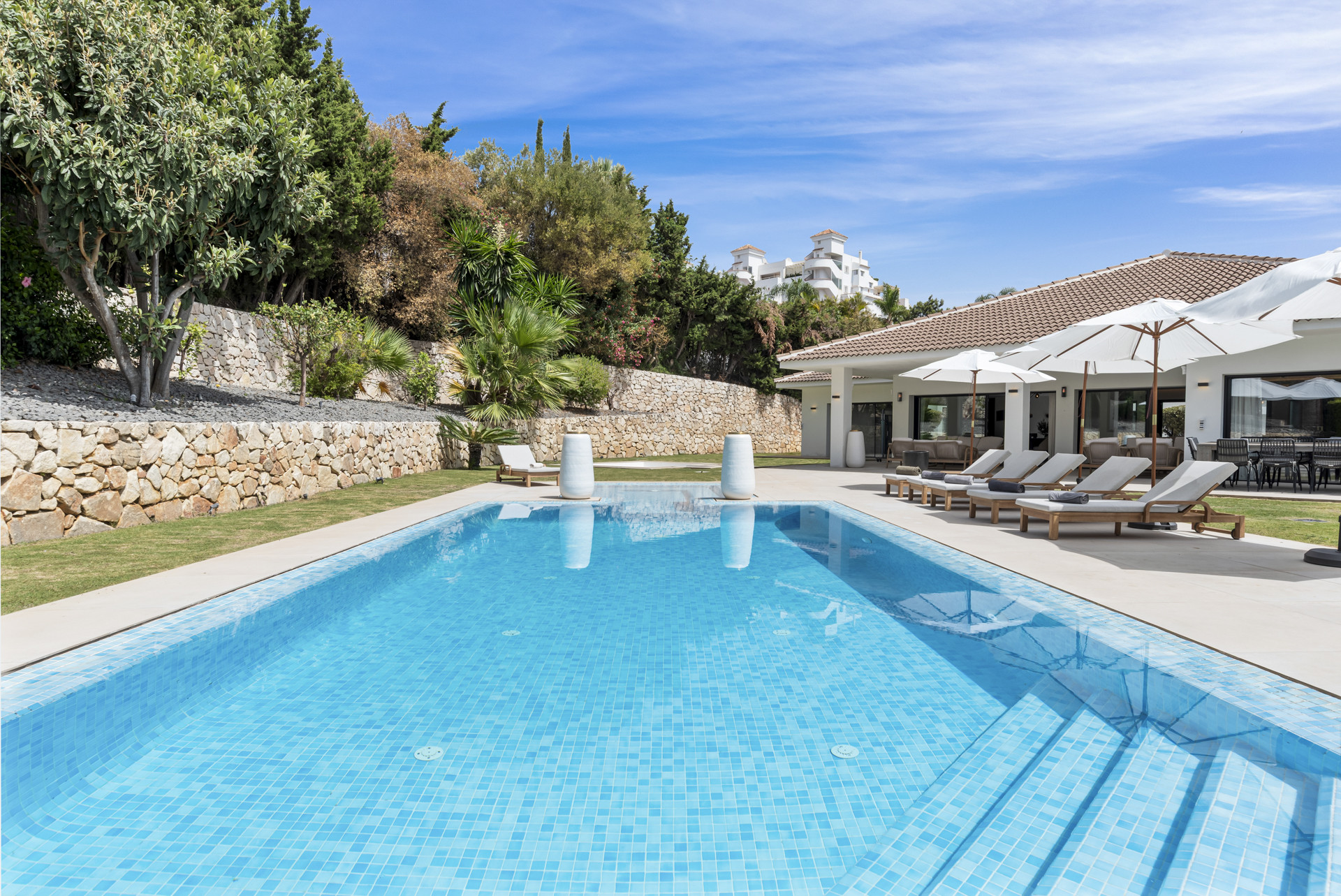 Panoramic view of the pool with the house and garden in the background.