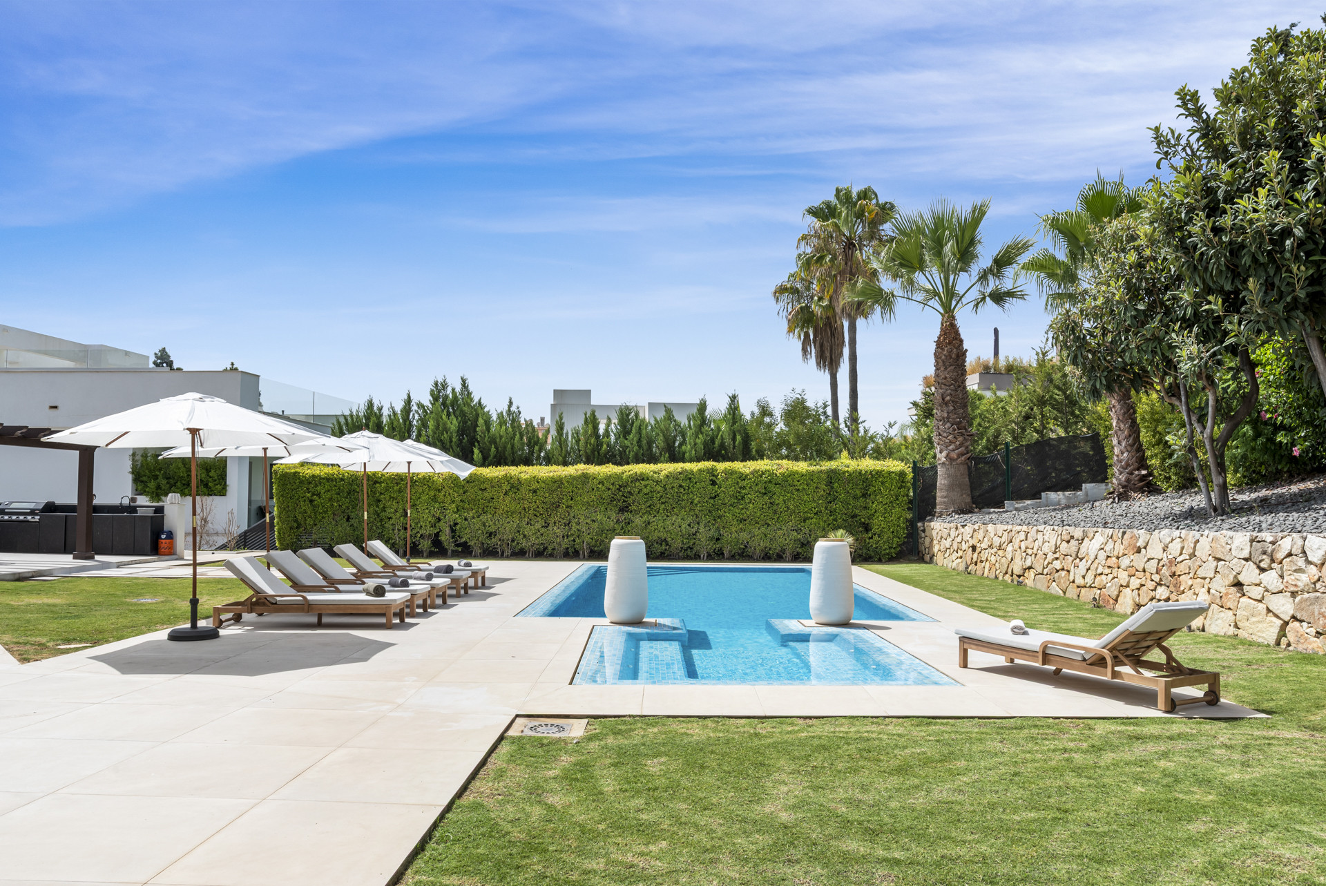 Side view of the pool area highlighting the loungers and surrounding garden.