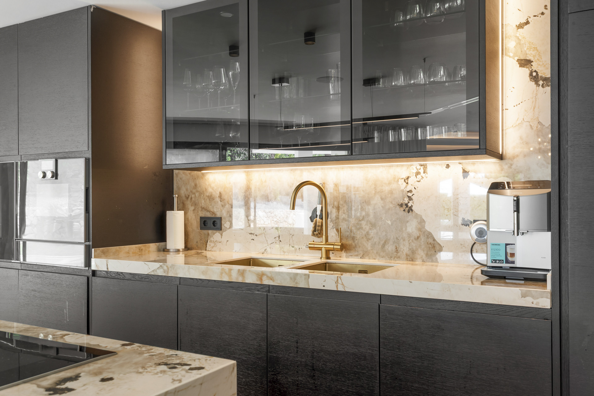 Detailed view of kitchen counter with double sink, gold faucet, and coffee machine.
