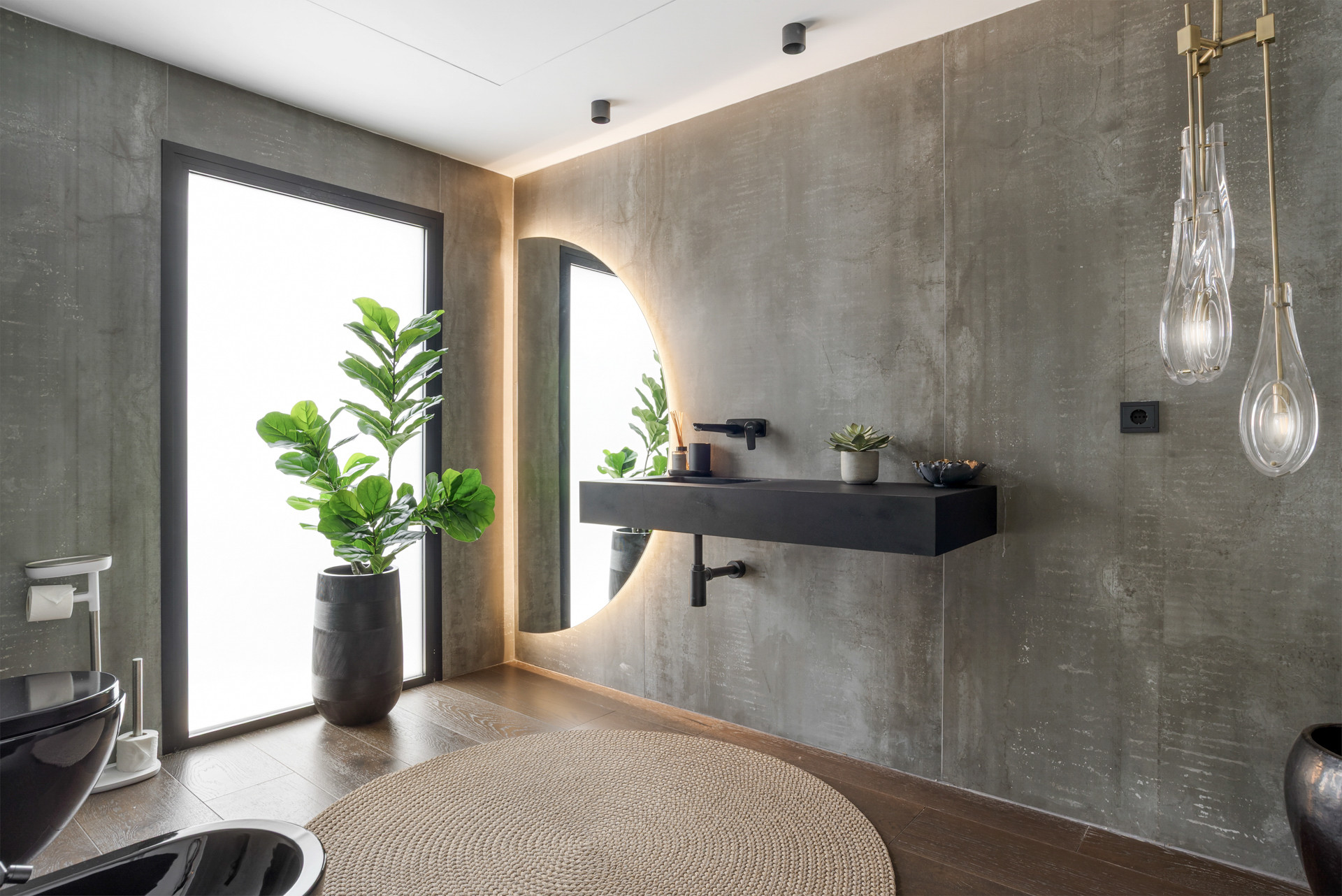 Modern bathroom with concrete walls, plants, and stylish lighting fixtures.