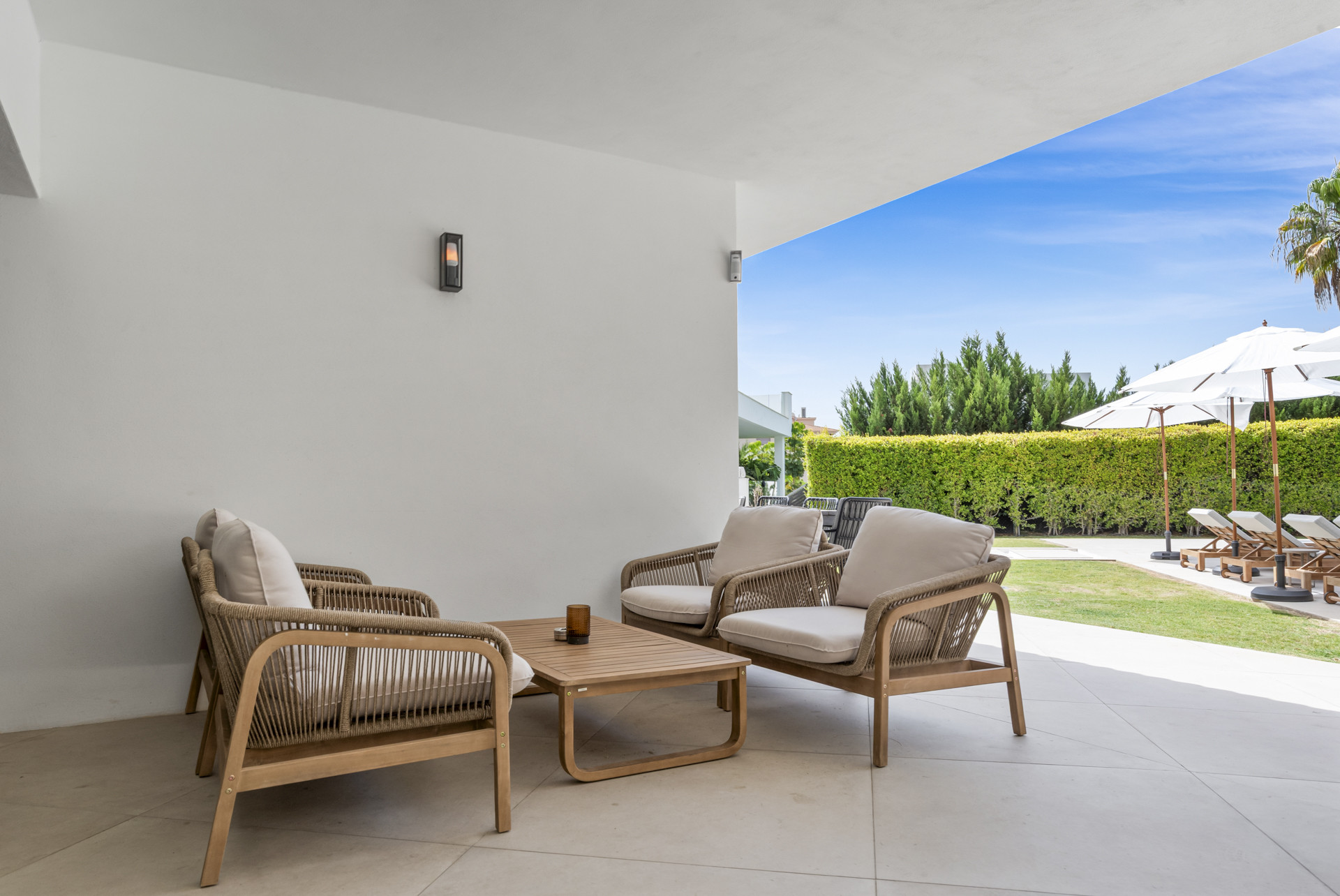 Covered patio with two rattan chairs and a coffee table overlooking the garden.