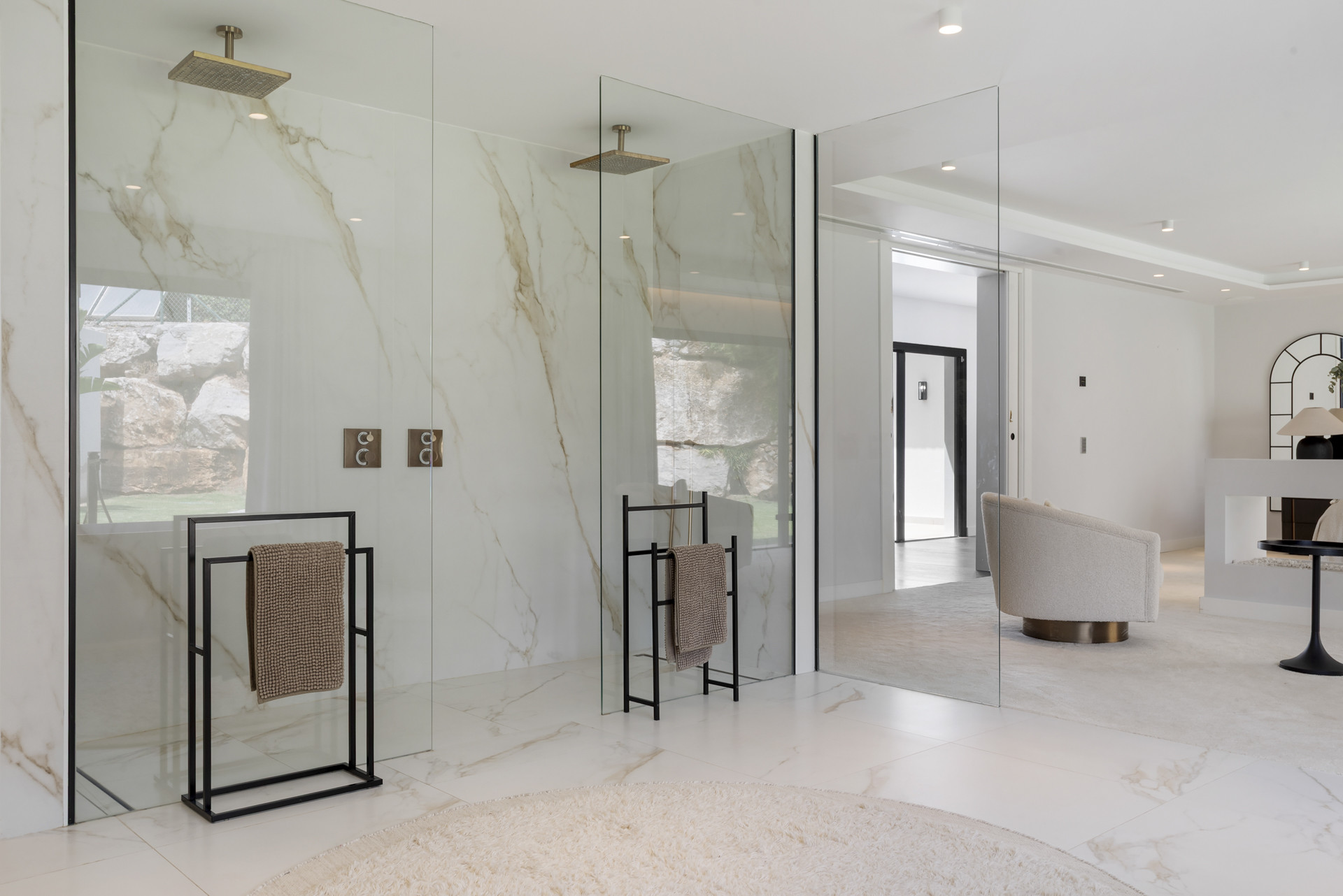 Modern bathroom with marble walls and glass shower doors.