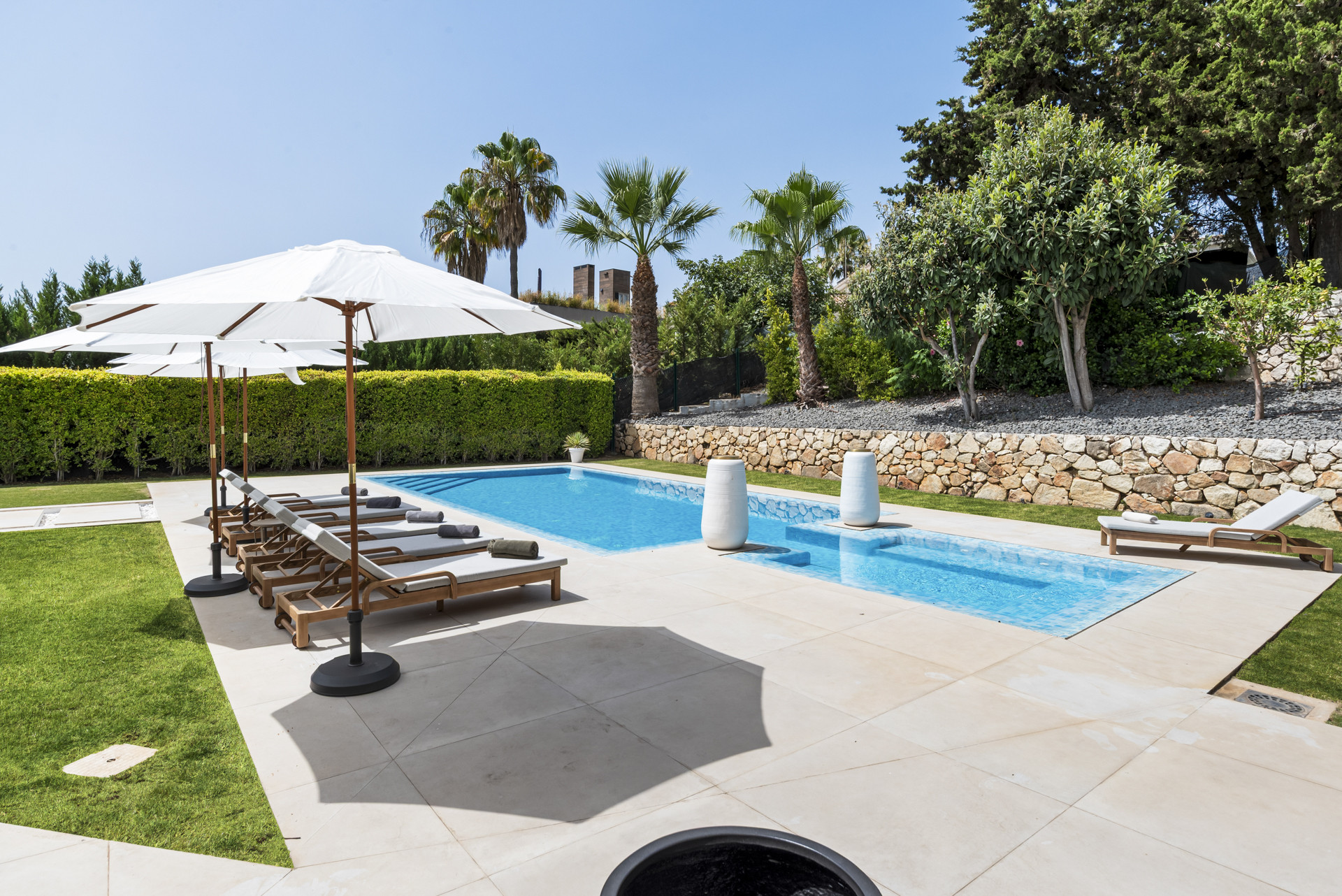 Another angle of the pool with loungers and greenery in the background.