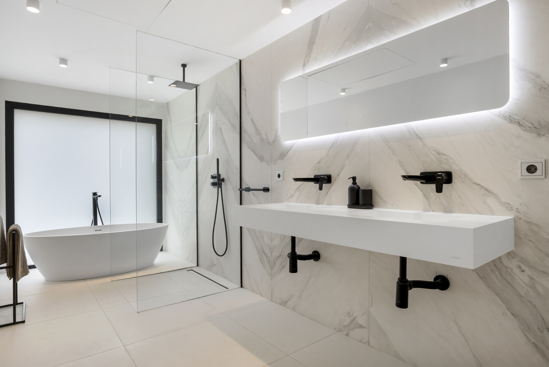 Contemporary bathroom including a freestanding tub, dual sinks, and glass shower.