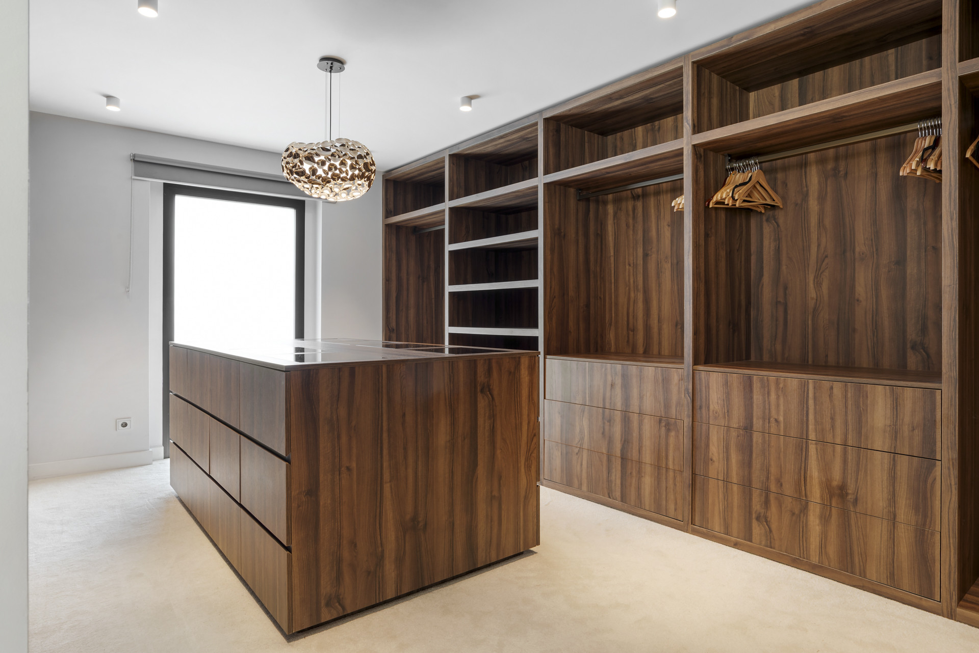 Walk-in closet with wood shelves and an island drawer unit.