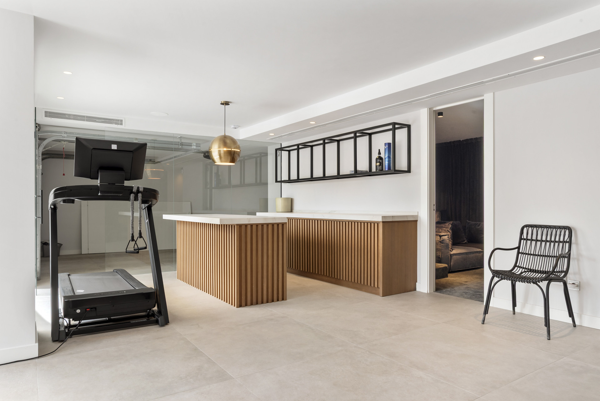 View of kitchen space featuring a bar, shelving, and treadmill, bright and open layout.