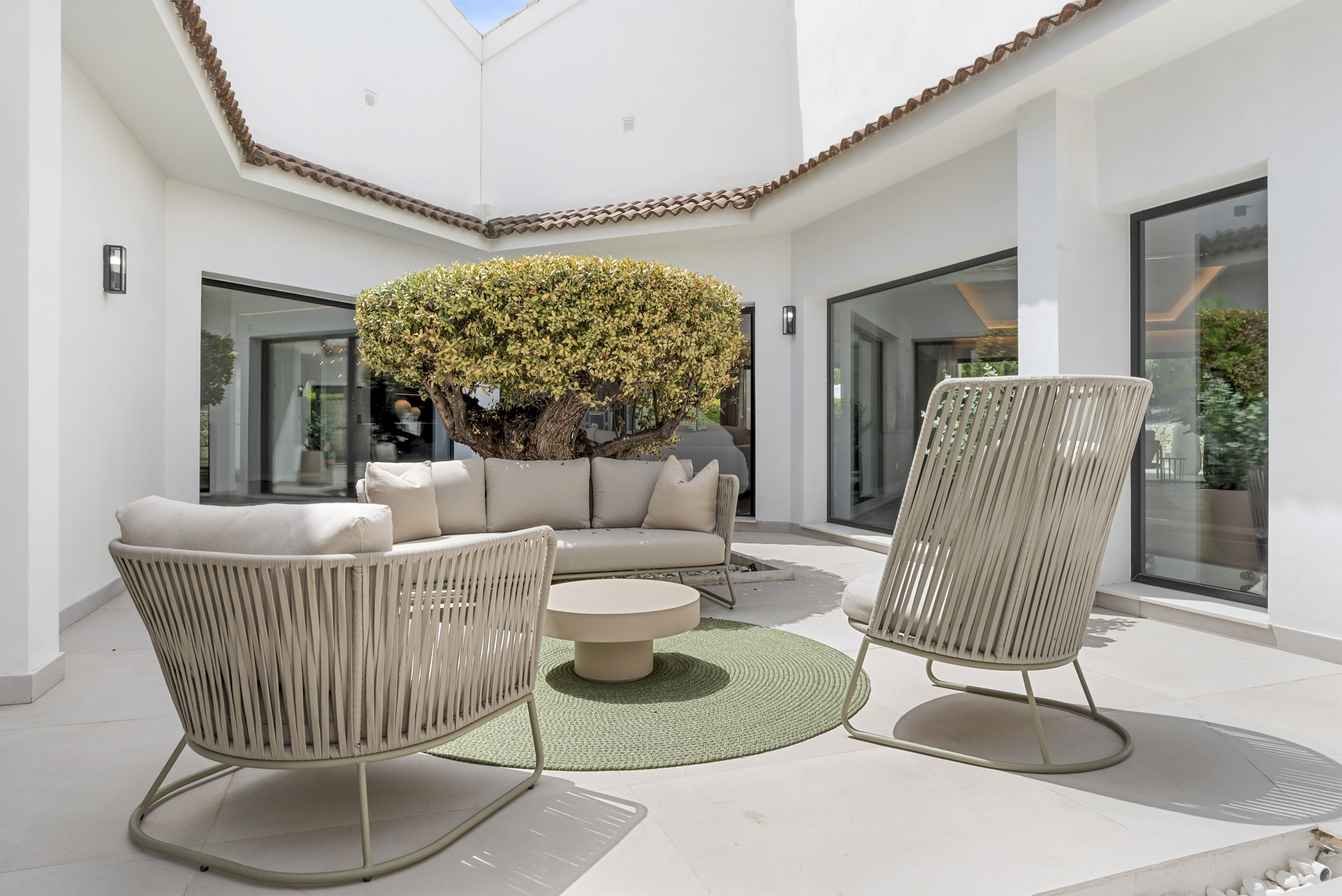 Outdoor seating area with a round table and tree feature in a light, airy courtyard.