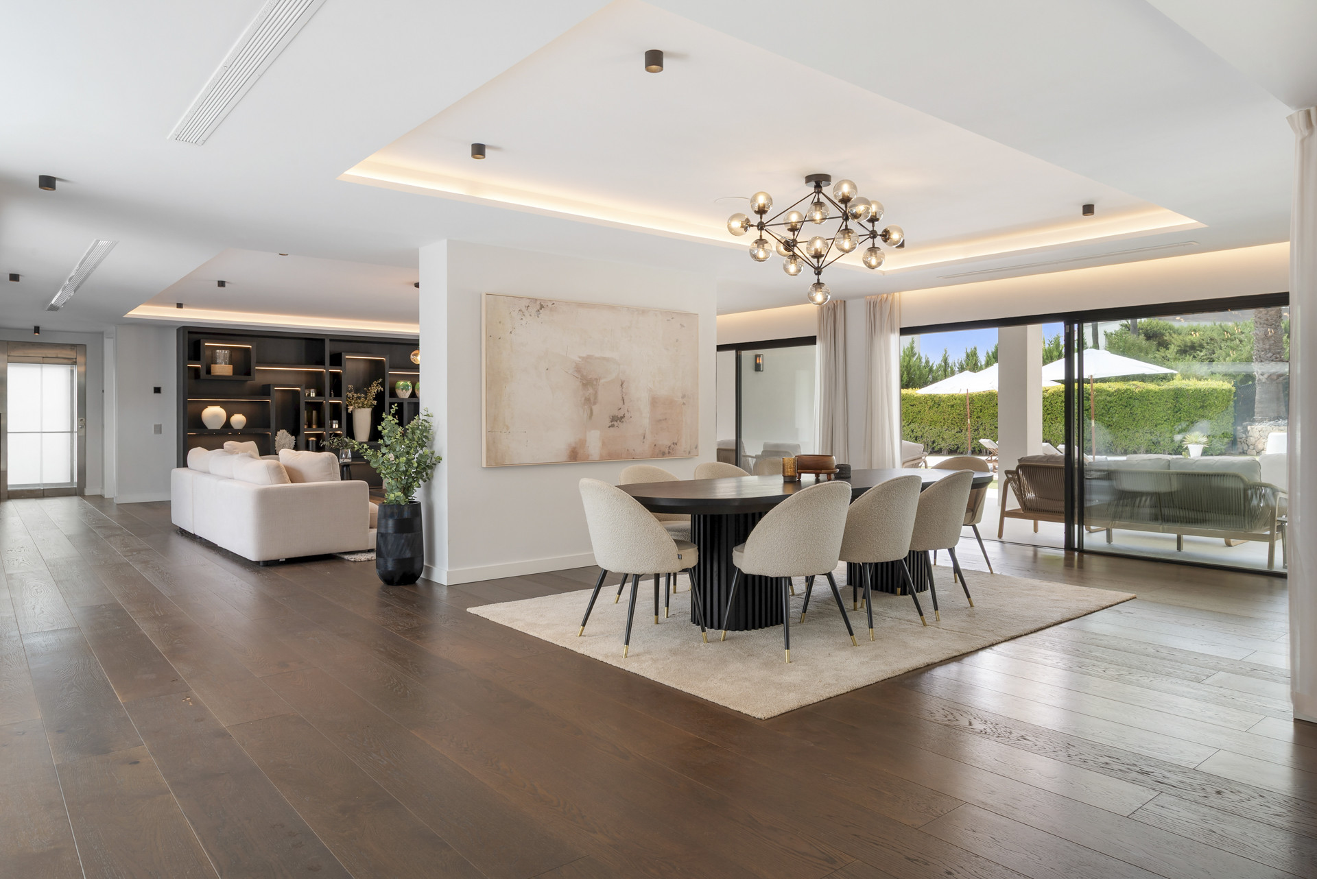 Contemporary dining area with a large table and windows leading to the garden patio.