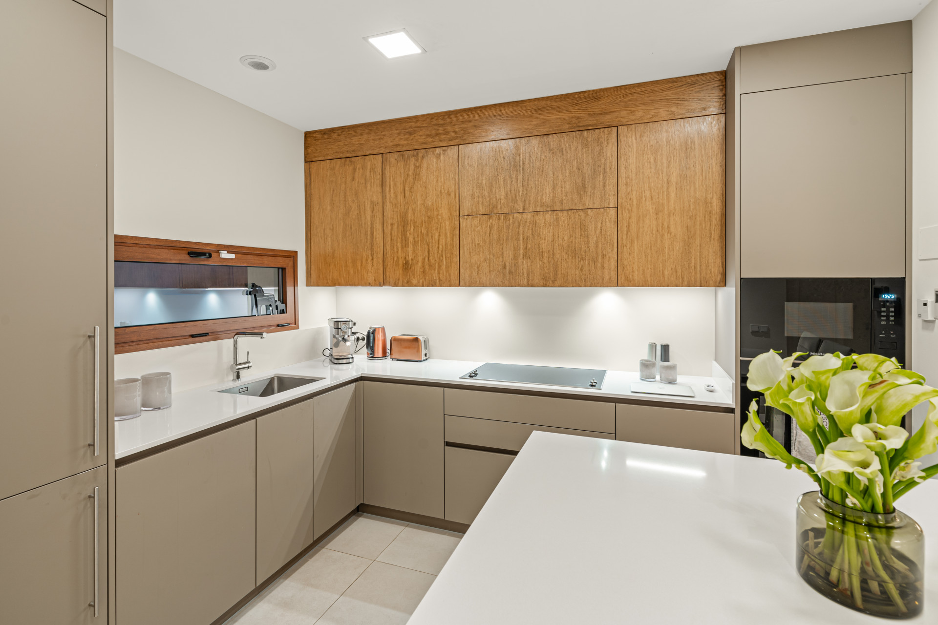 Modern kitchen with wood accents and white cabinetry, featuring stainless steel appliances and a sink.