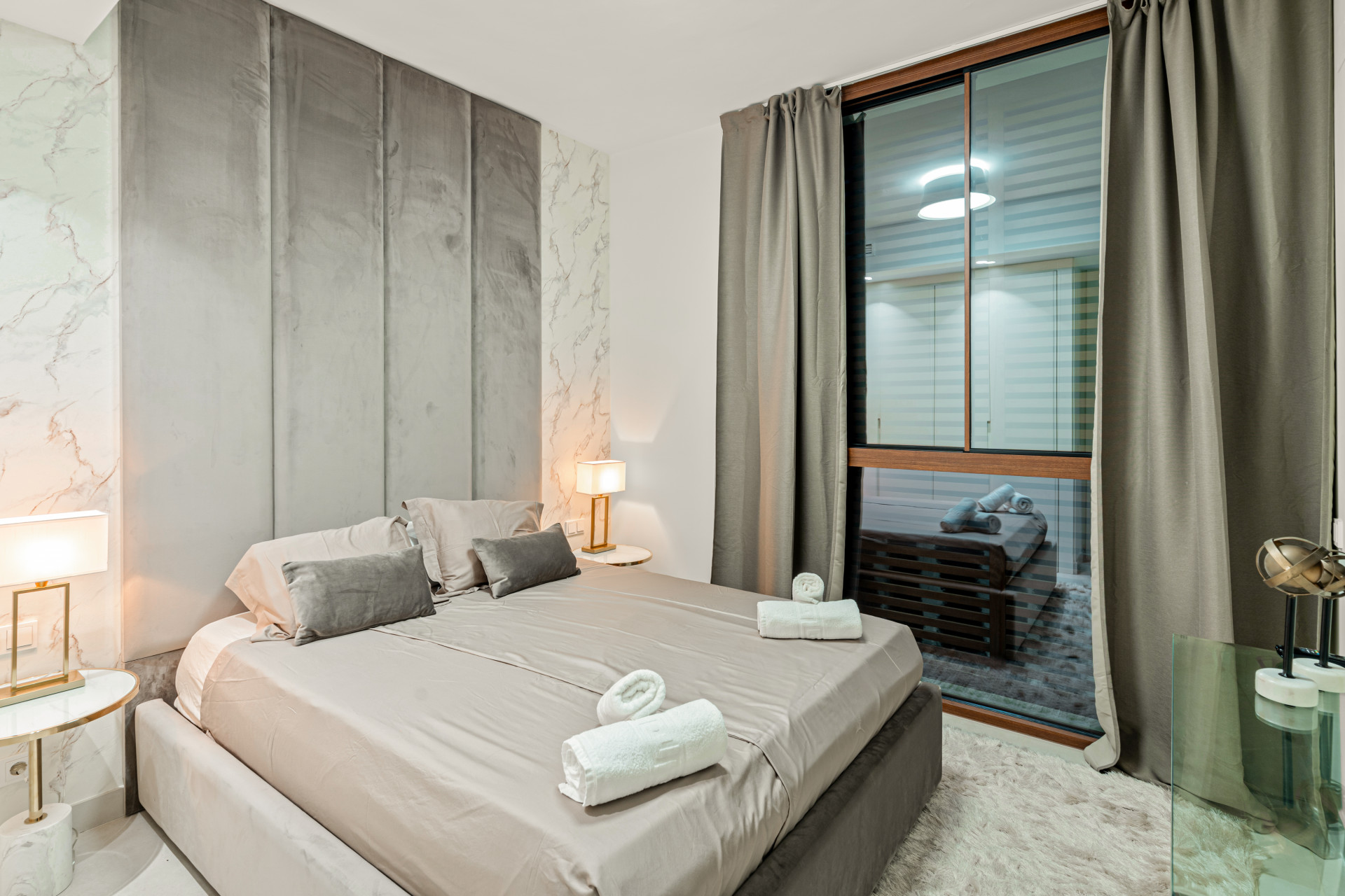 Bedroom with gray accent wall, modern bedding, and window with curtains.