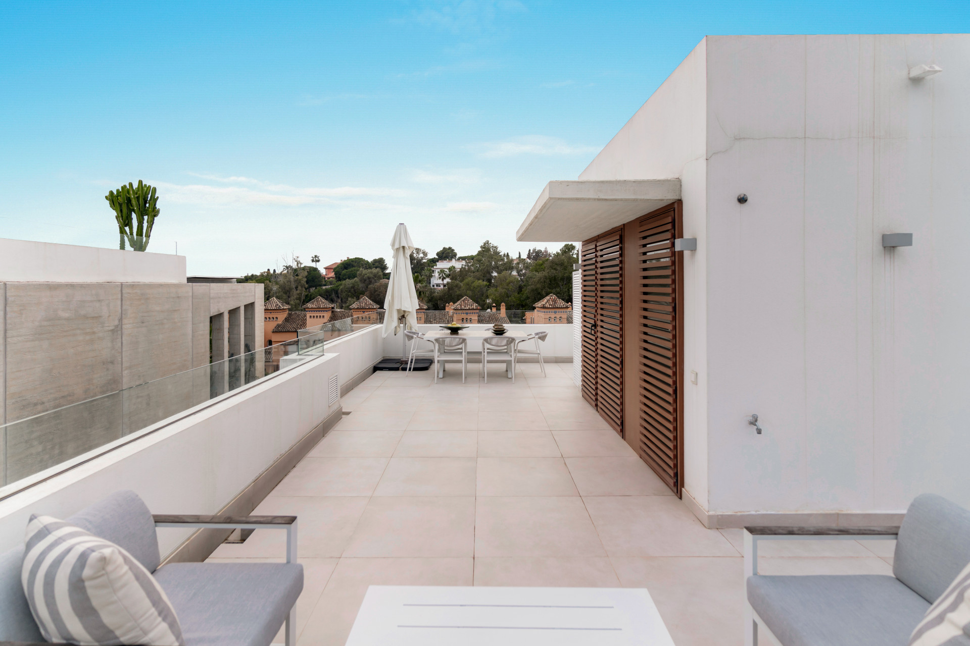 Rooftop terrace with seating and a clear view of neighboring villas.