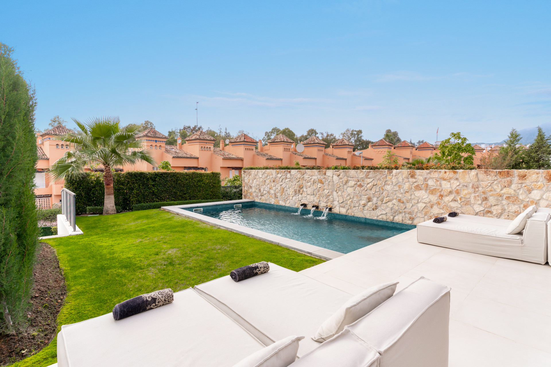 Outdoor space with a pool, loungers, and garden lawn in a residential setting.