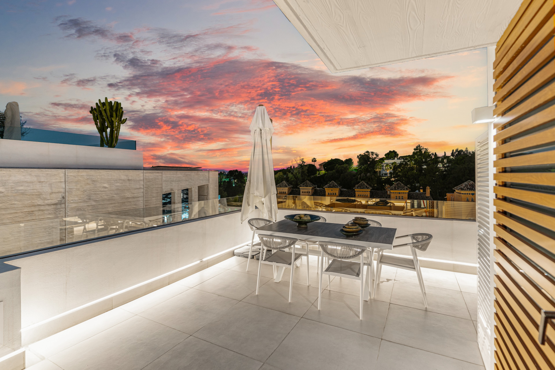 Outdoor terrace with dining table and stunning sunset view.