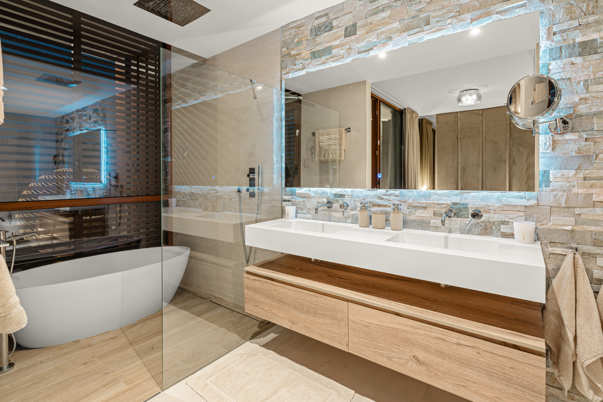 Elegant bathroom with glass shower, wooden vanity, and stone accents.