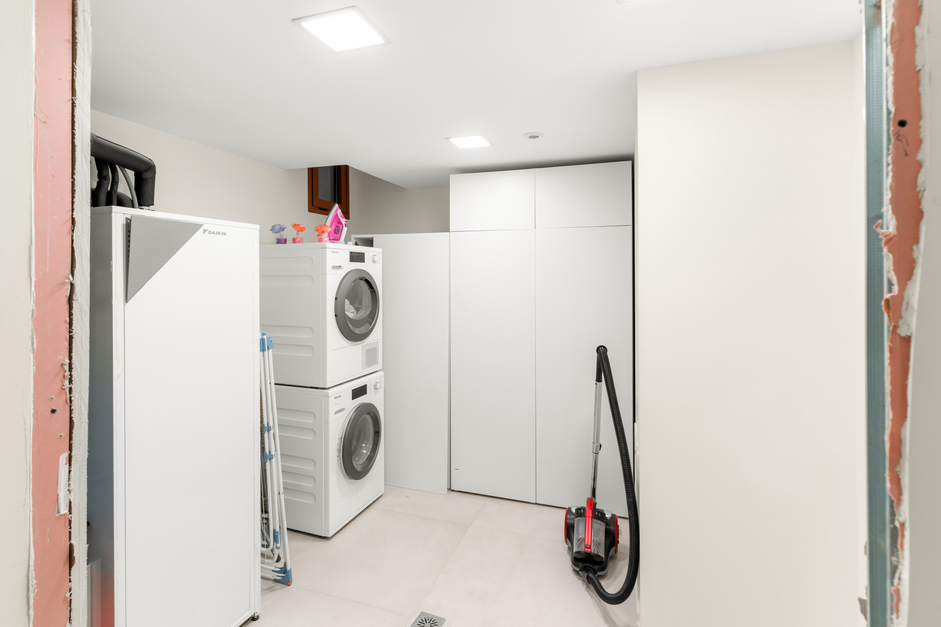 Laundry room featuring stacked washer and dryer with storage.