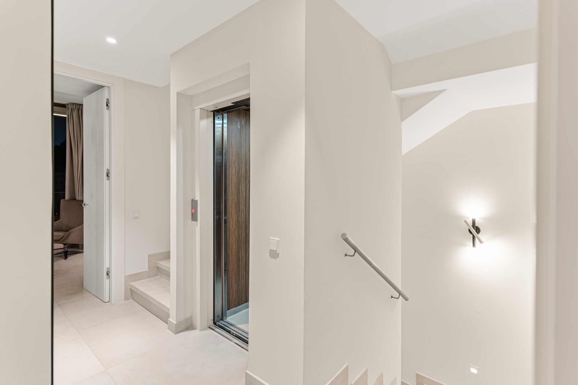 Interior hallway with elevator and stairs in neutral tones.