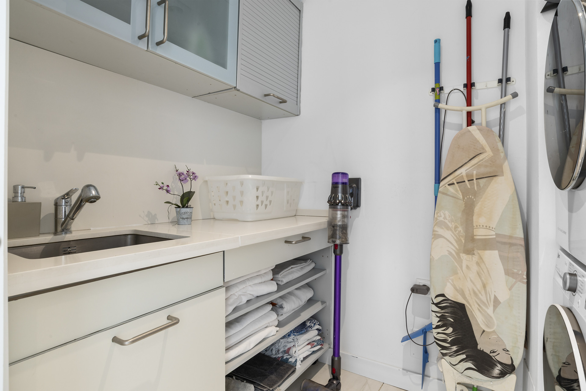 A laundry area with a sink, storage cabinets, and space for linens and cleaning equipment.