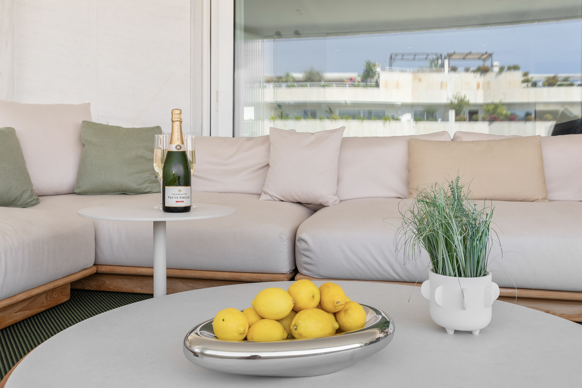 Close-up of a table displaying champagne, glasses, and a bowl of lemons on a stylish surface.