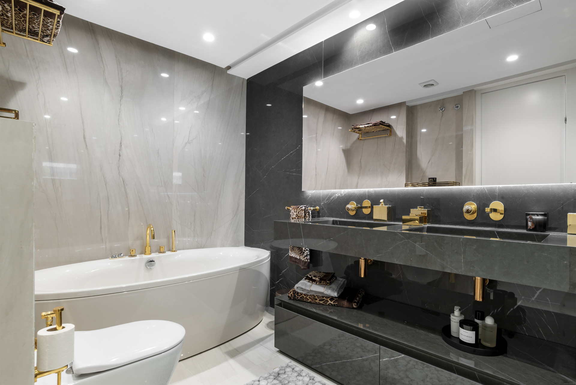 Spacious bathroom with a freestanding tub and a dual sink vanity with gold fixtures.