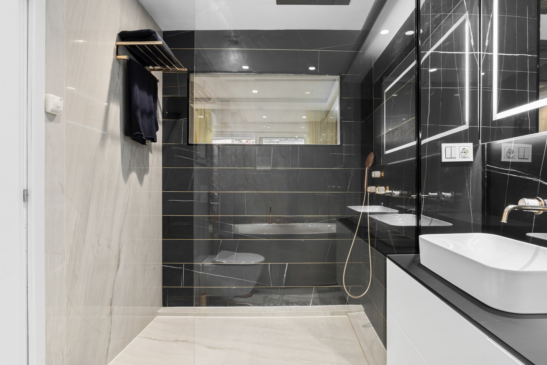 Modern bathroom with a walk-in shower, black tiles, and contemporary fixtures.