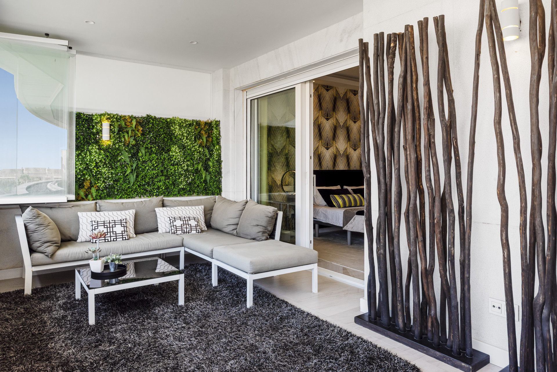 A cozy lounge area with a green wall and a large sofa, featuring decorative cushions and a coffee table.