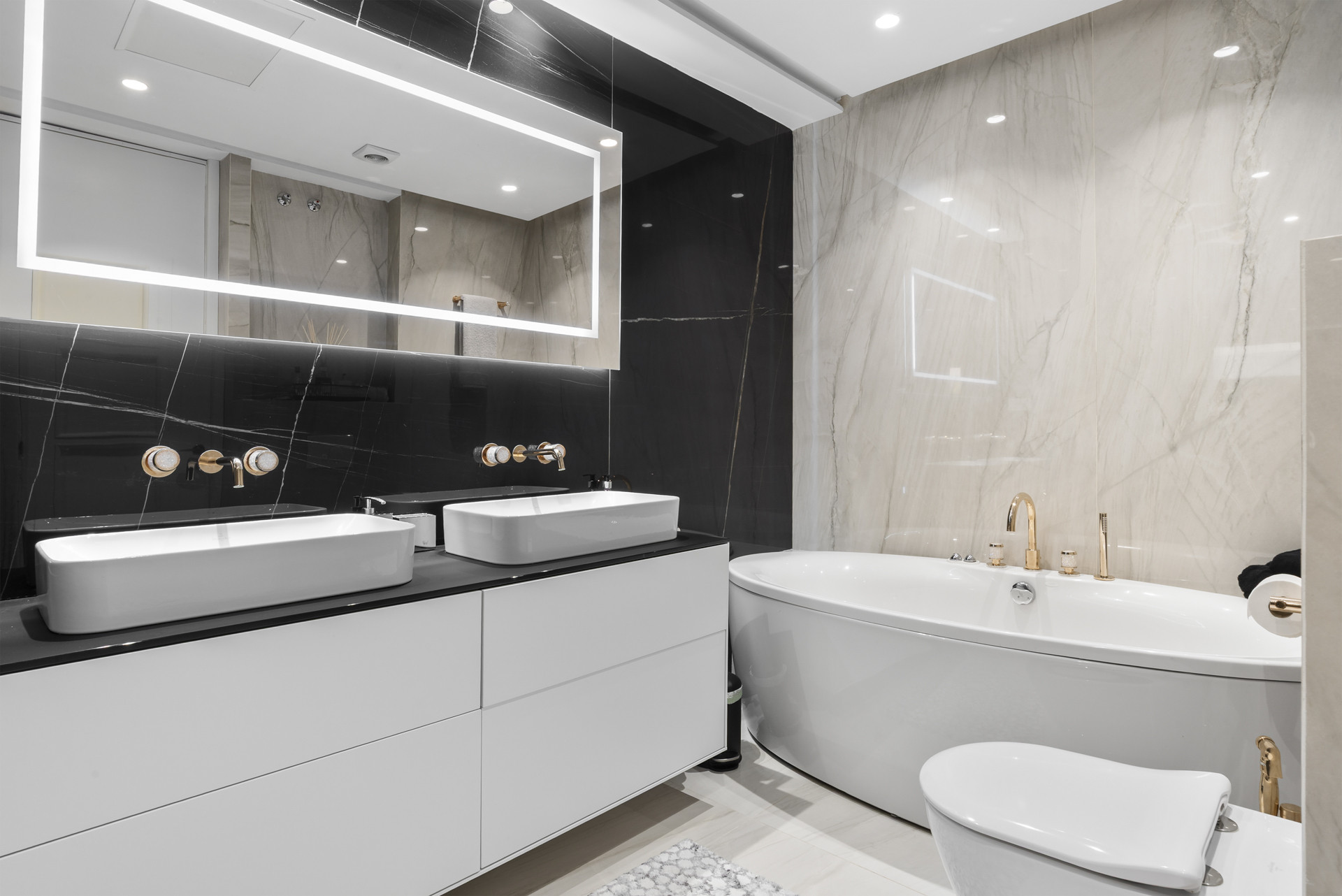 Luxurious bathroom with dual sinks, elegant bathtub, and marble tiles.