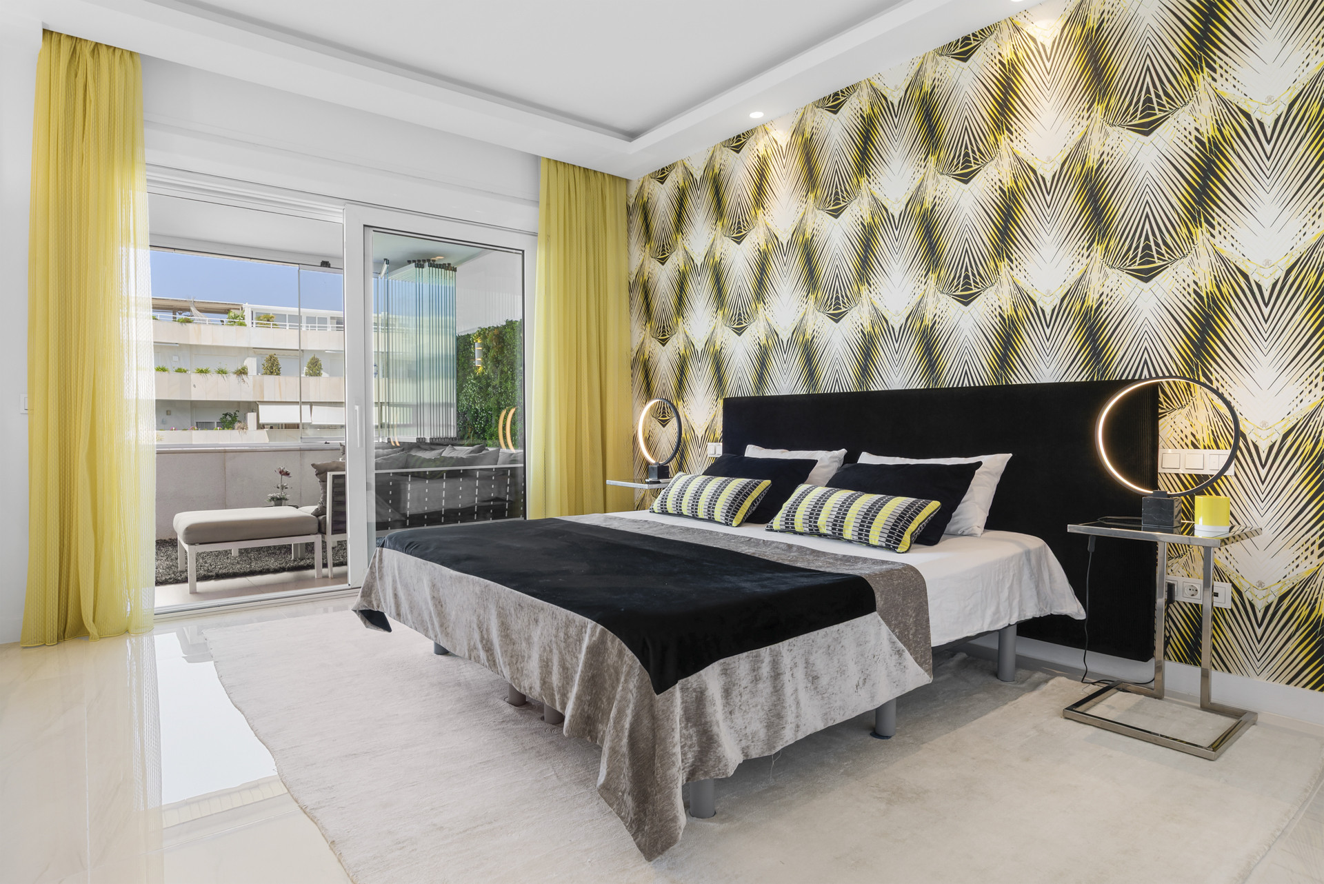 Stylish bedroom with a patterned feature wall and large sliding doors to a terrace.