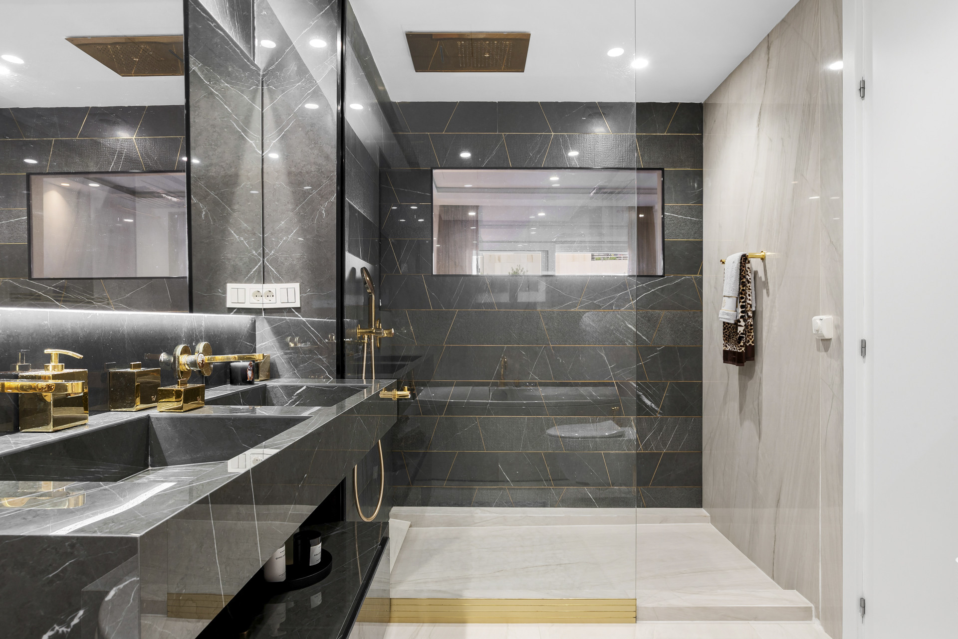 Modern bathroom featuring glass-enclosed shower, two sinks, and stylish tile accents.