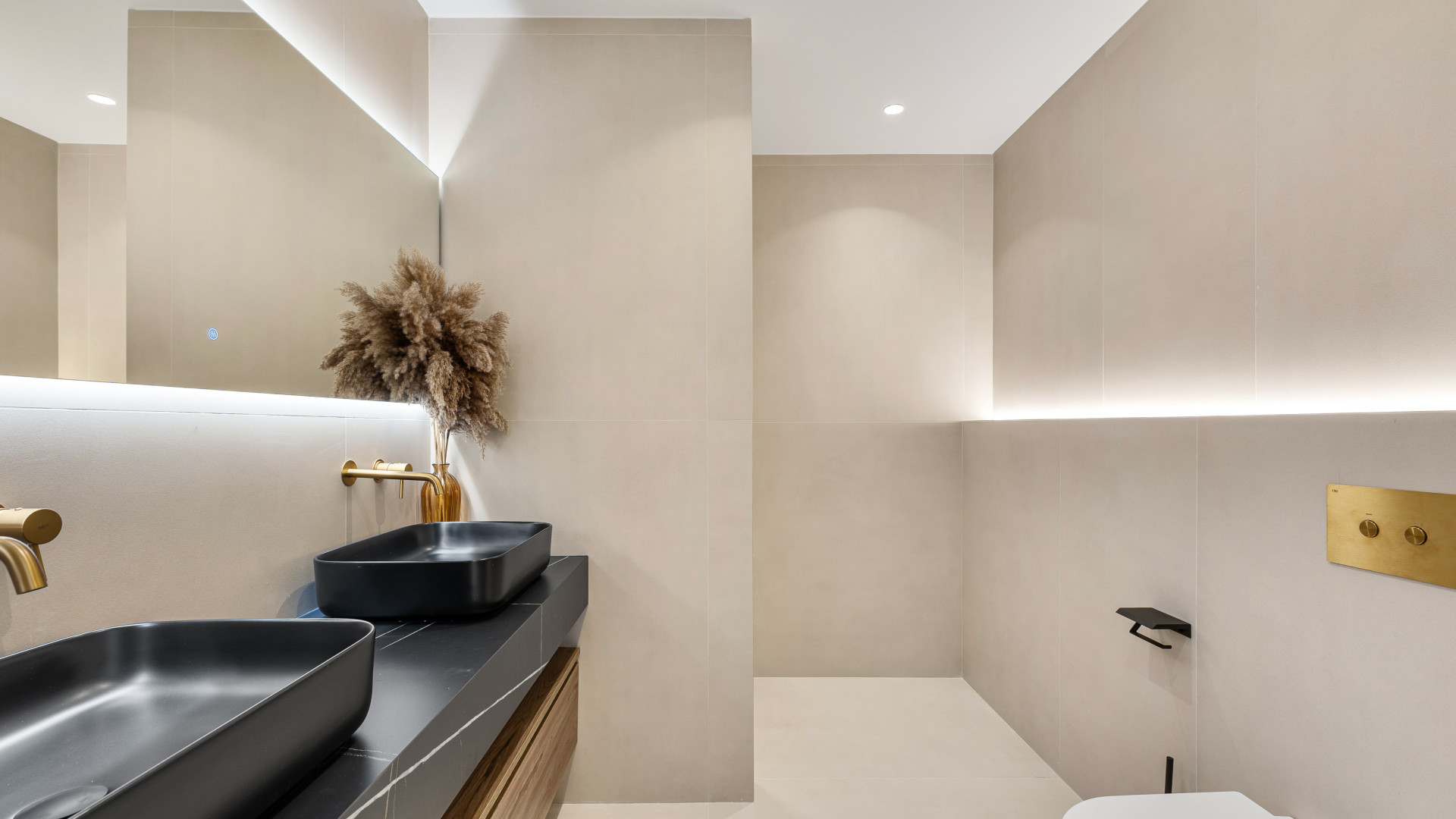 Double sink vanity with two black sinks, decorative plant, and soft lighting.