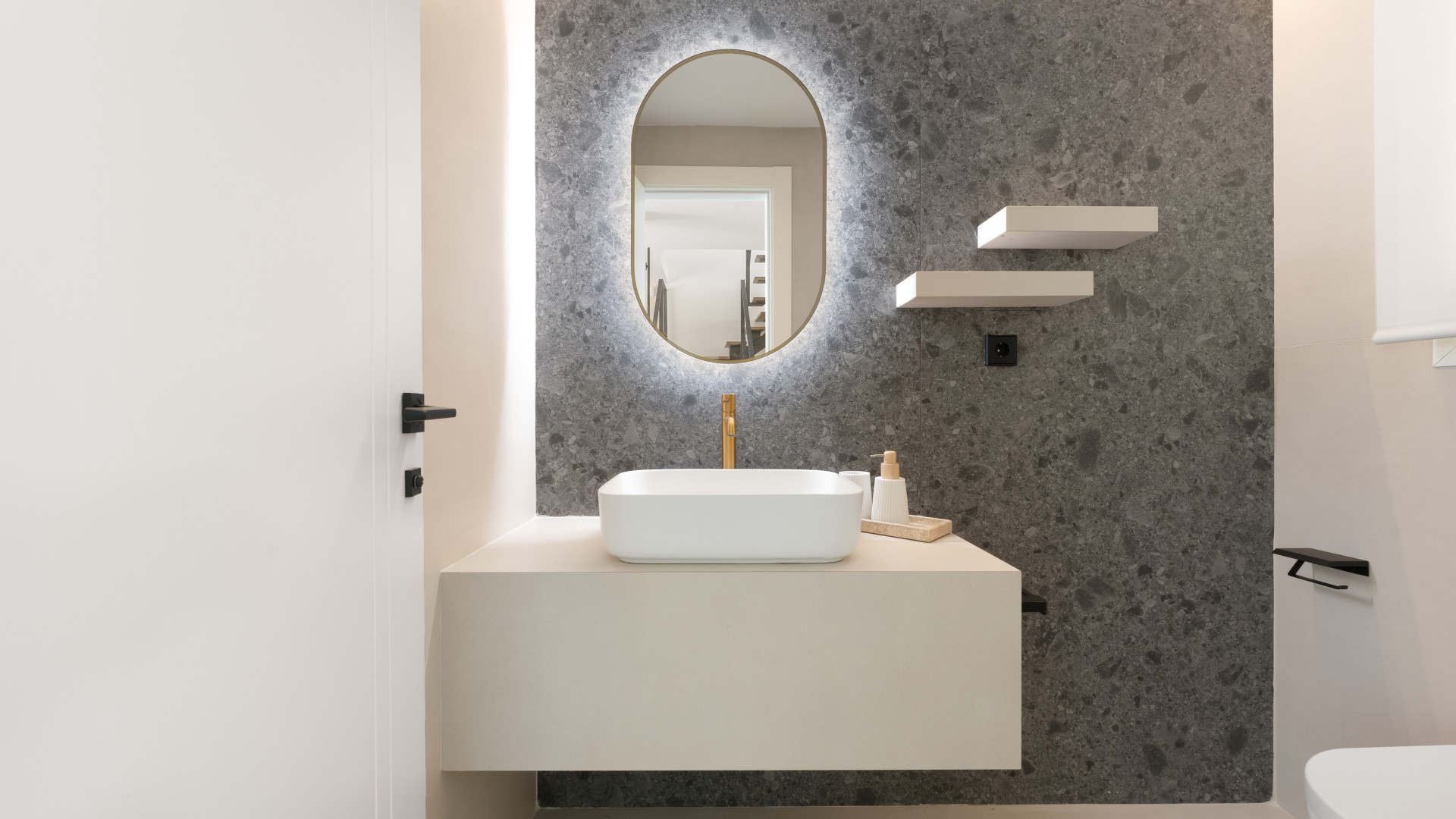 Stylish bathroom with a round mirror, sink, and gray stone wall accents.