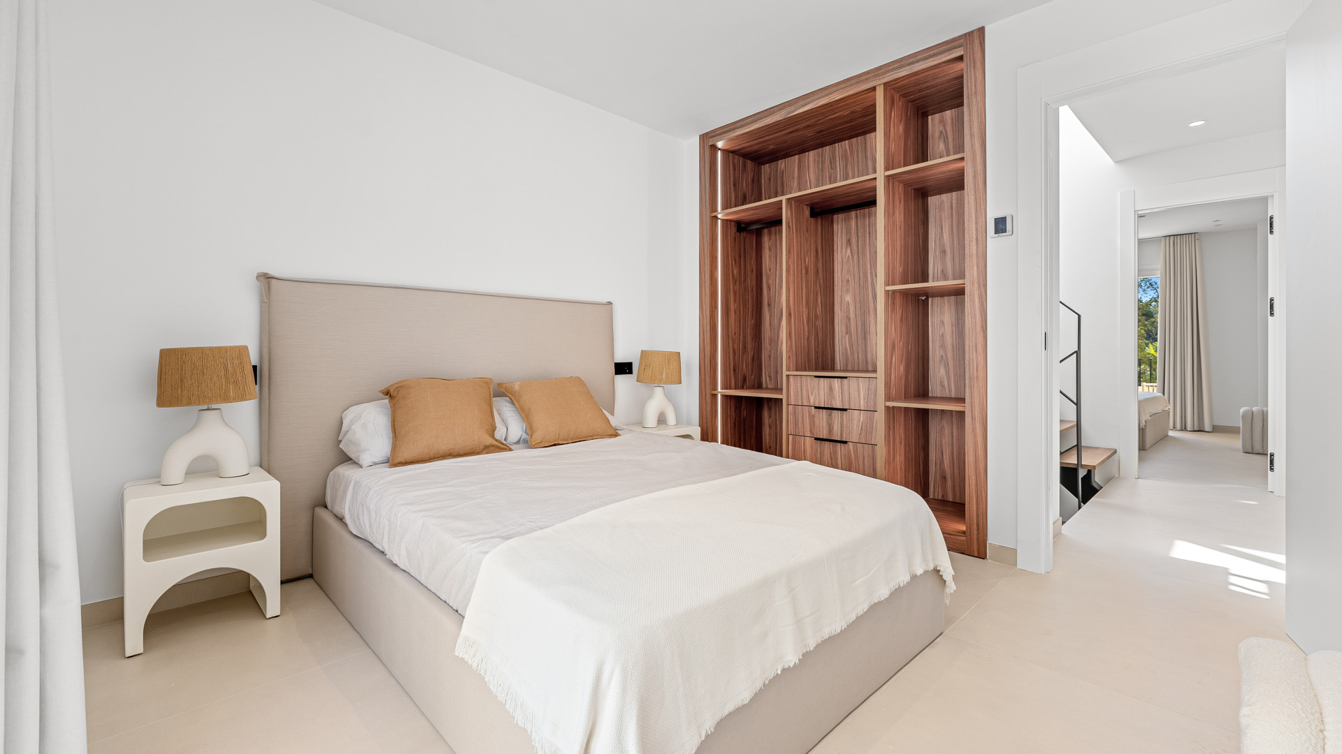 Cozy bedroom with built-in wooden closet, decorative pillows, and soft natural light.