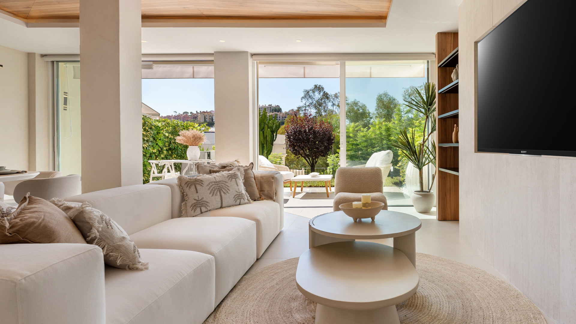 Living room with white sofas, circular coffee table, and large glass doors leading outside.