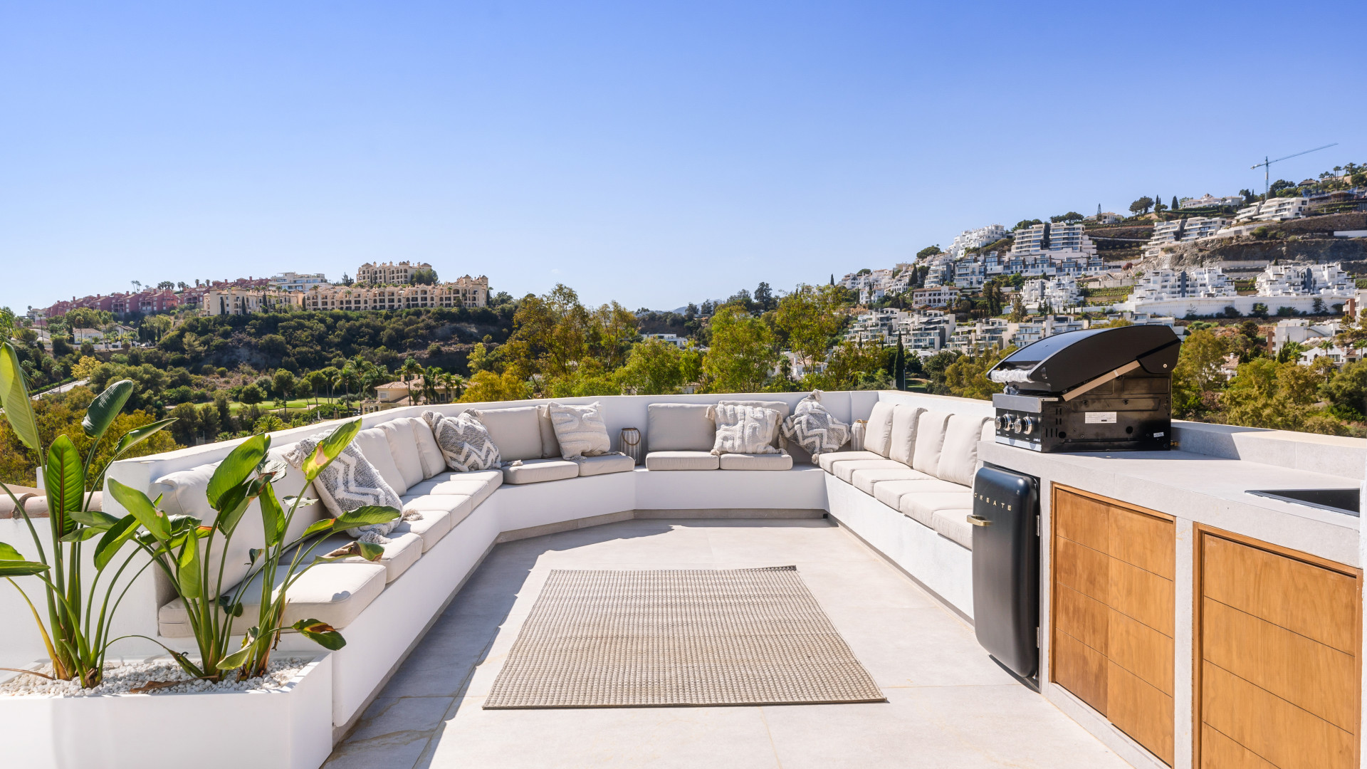 Spacious terrace with a sectional sofa, outdoor grill, and a view of the hills.