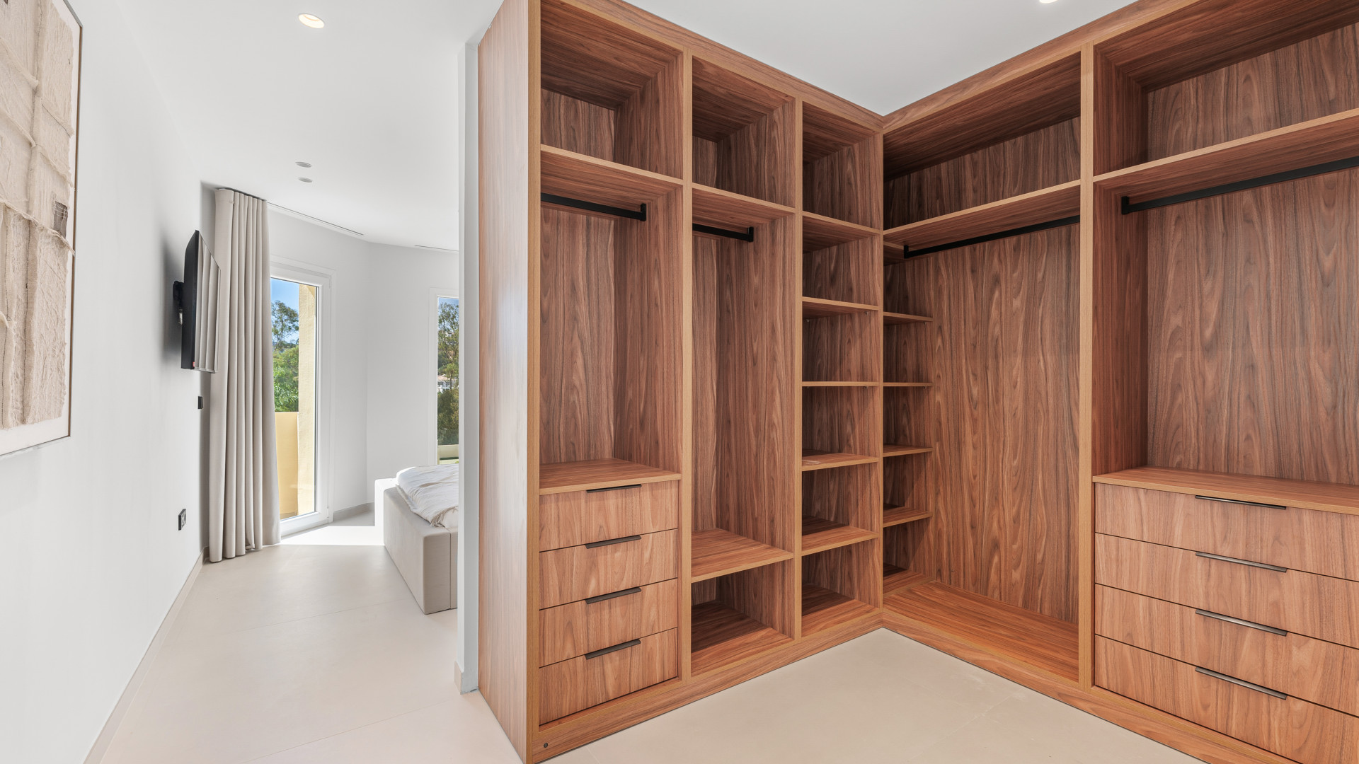 Walk-in closet with wooden shelves and drawers. Open design offers easy access to stored items.