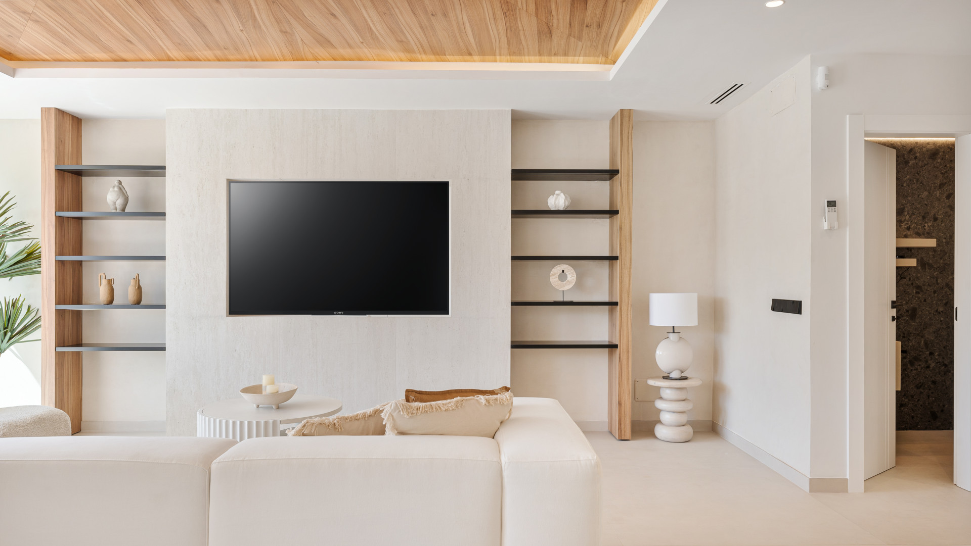 Living room corner with TV mounted on wall, modern decor, and a doorway leading elsewhere.