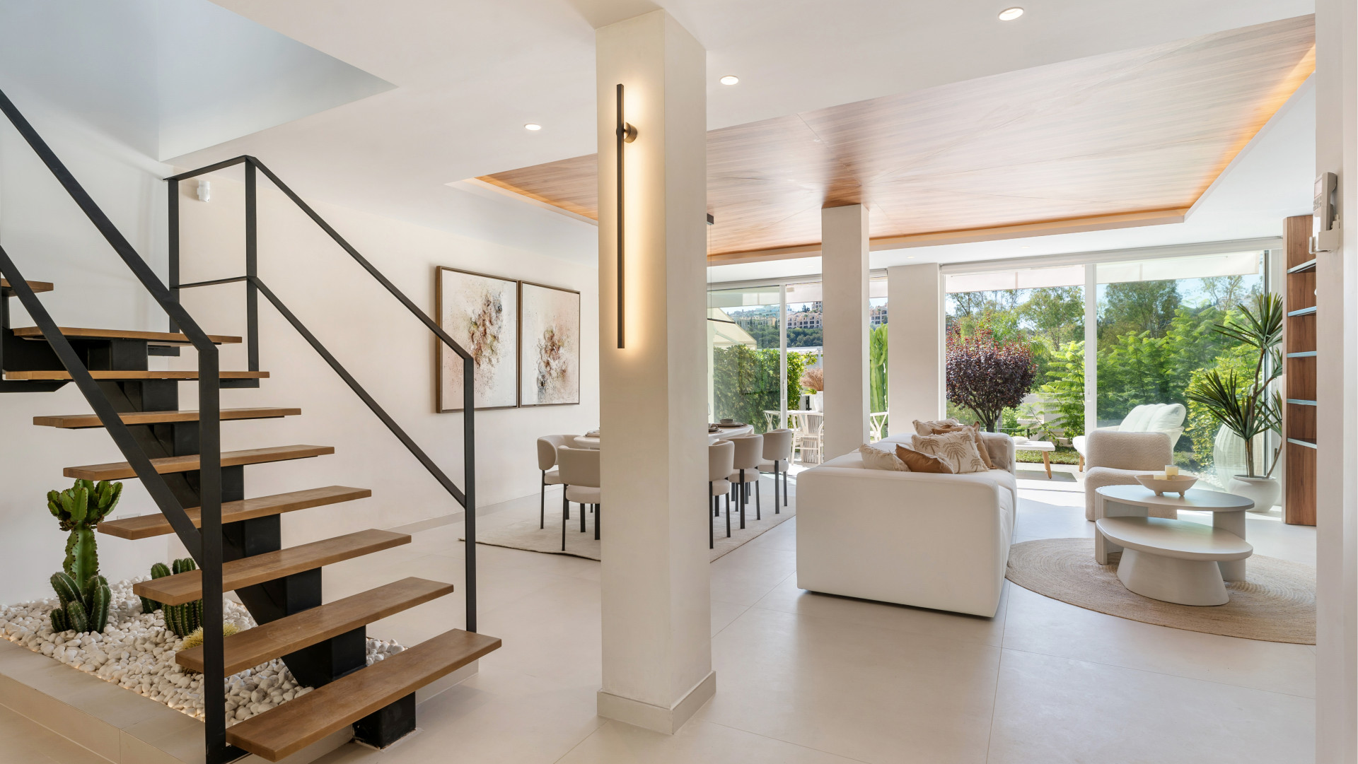 Spacious living area with a view of the garden, featuring modern furniture and decorative plants.