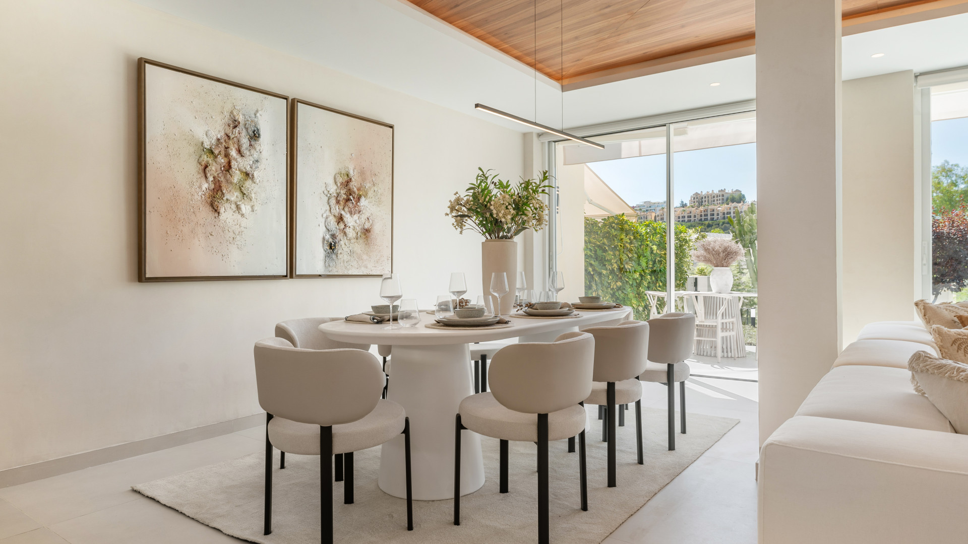 Close-up of the dining table set for a meal, framed art on the wall, greenery outside visible.