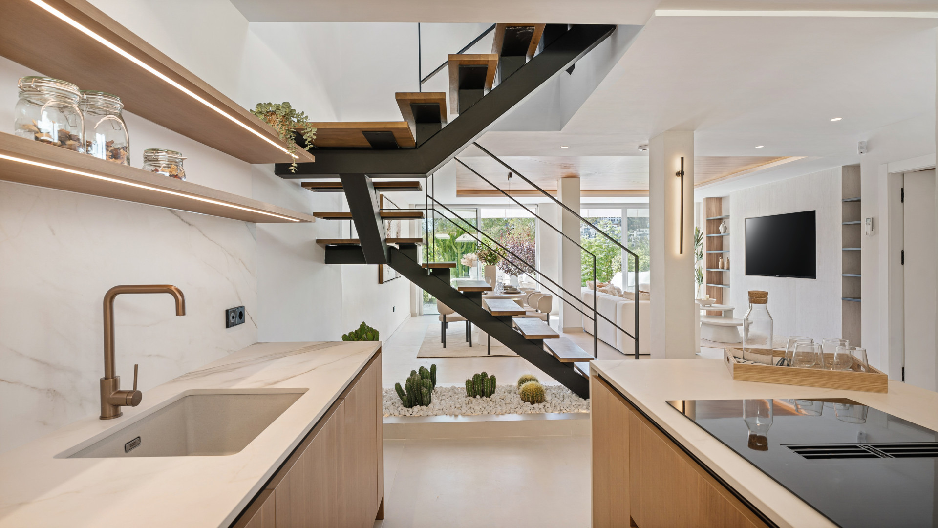 Kitchen angle showing modern cabinetry, sink, and visible staircase leading to the upper level.