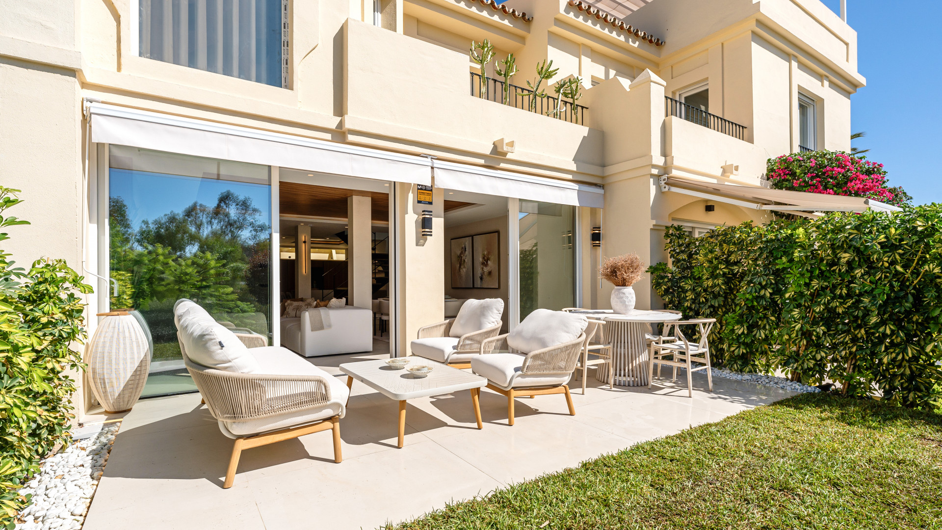 Outdoor terrace with seating arrangement, green plants, and access to the interior of the house.